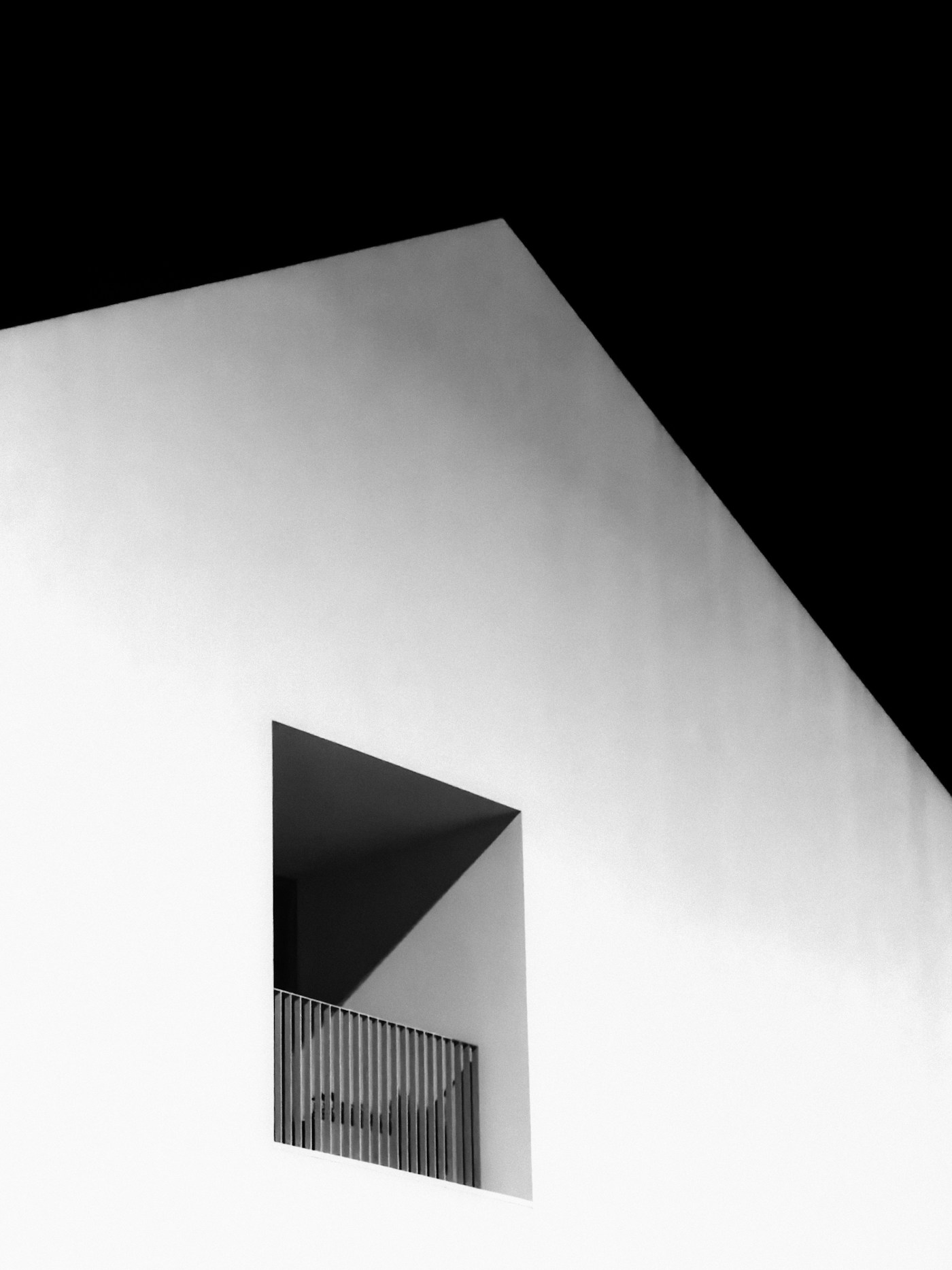 Square opening cut into a white wall against a black sky