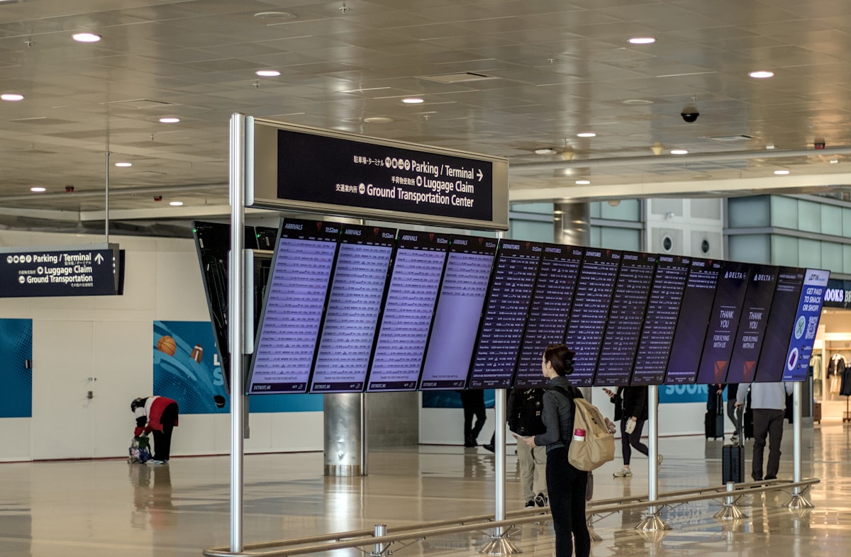 Traveler with a backpack checking an airport flight information board for delays