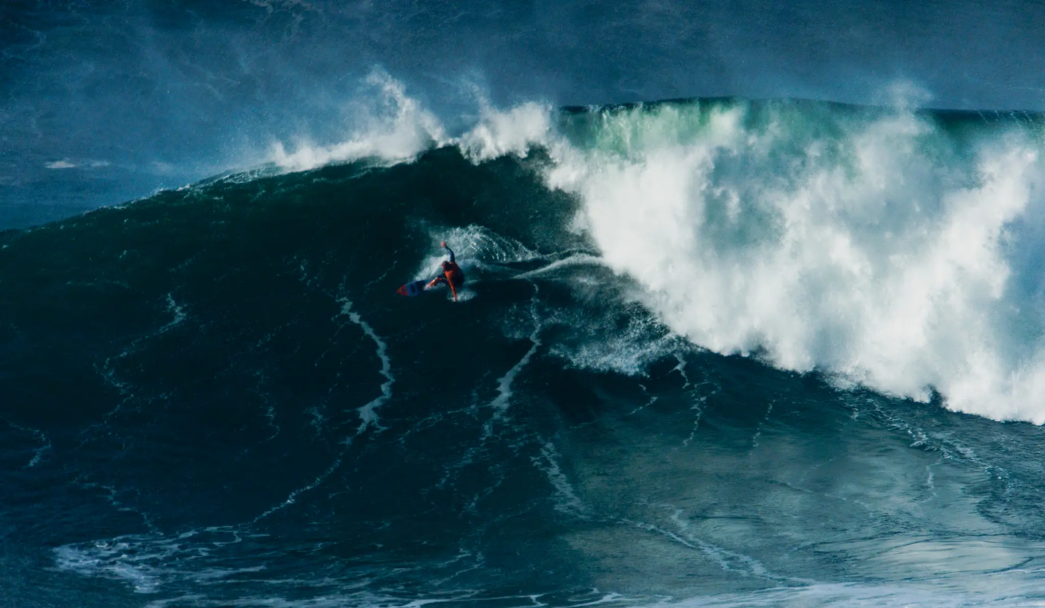 Aerial view of a surfer carving across a large breaking wave