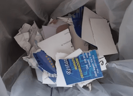 biglietti da visita strappati in un cestino della spazzatura