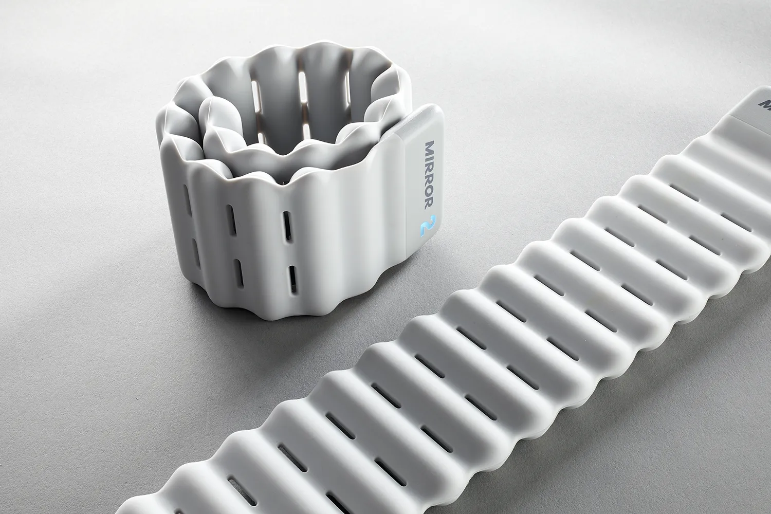 Mirror connected ankle weight shown coiled beside a second weight laid flat