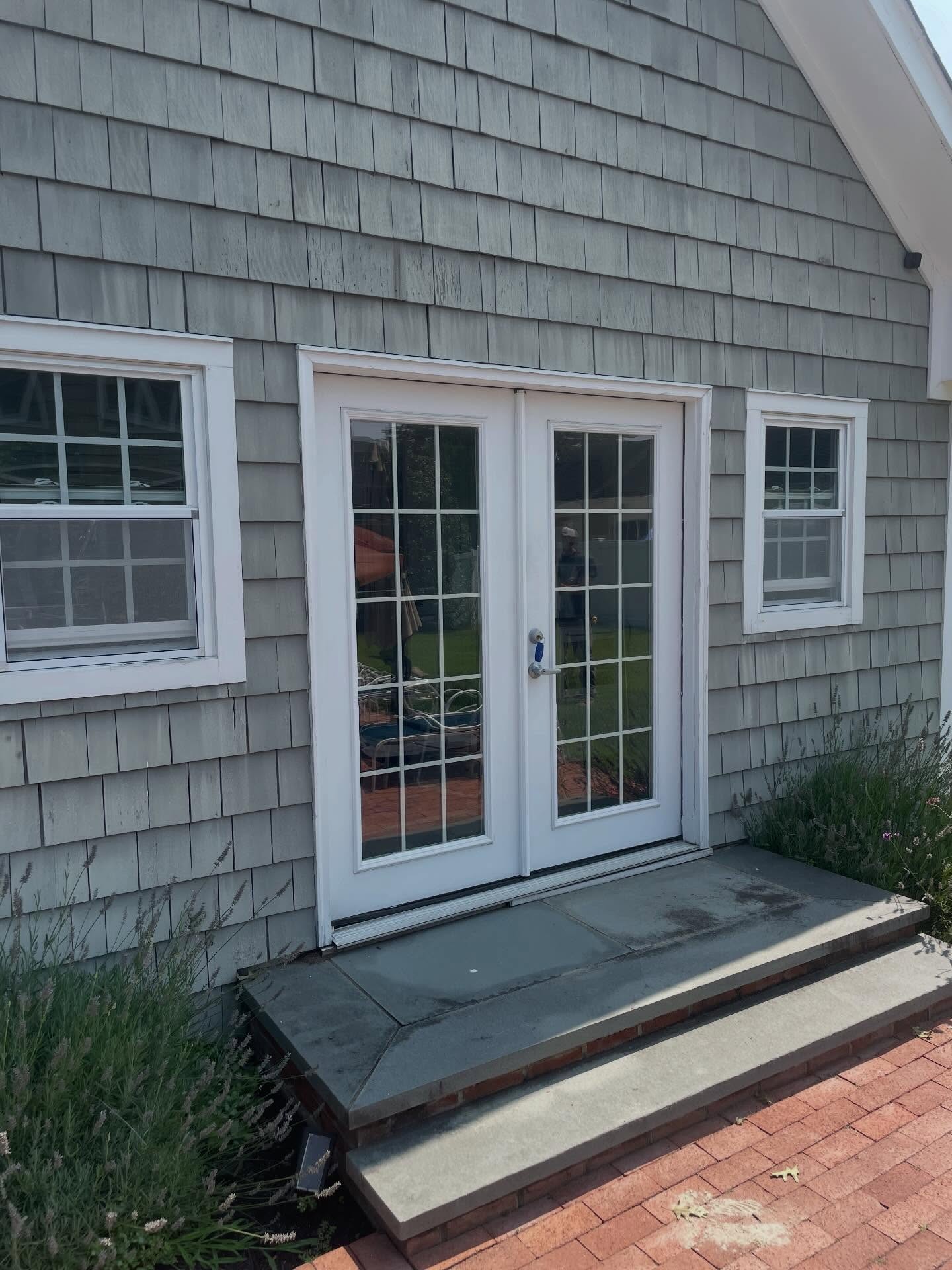 New white French patio doors installed in cedar-shingle wall
