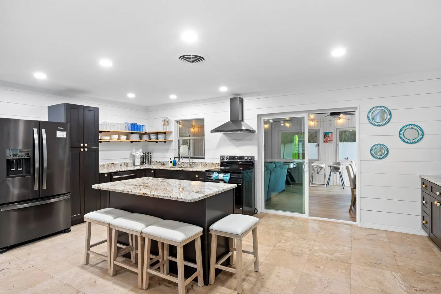 Kitchen with island with bar stools and black appliances at Pickleball Resort, Bradenton, Florida