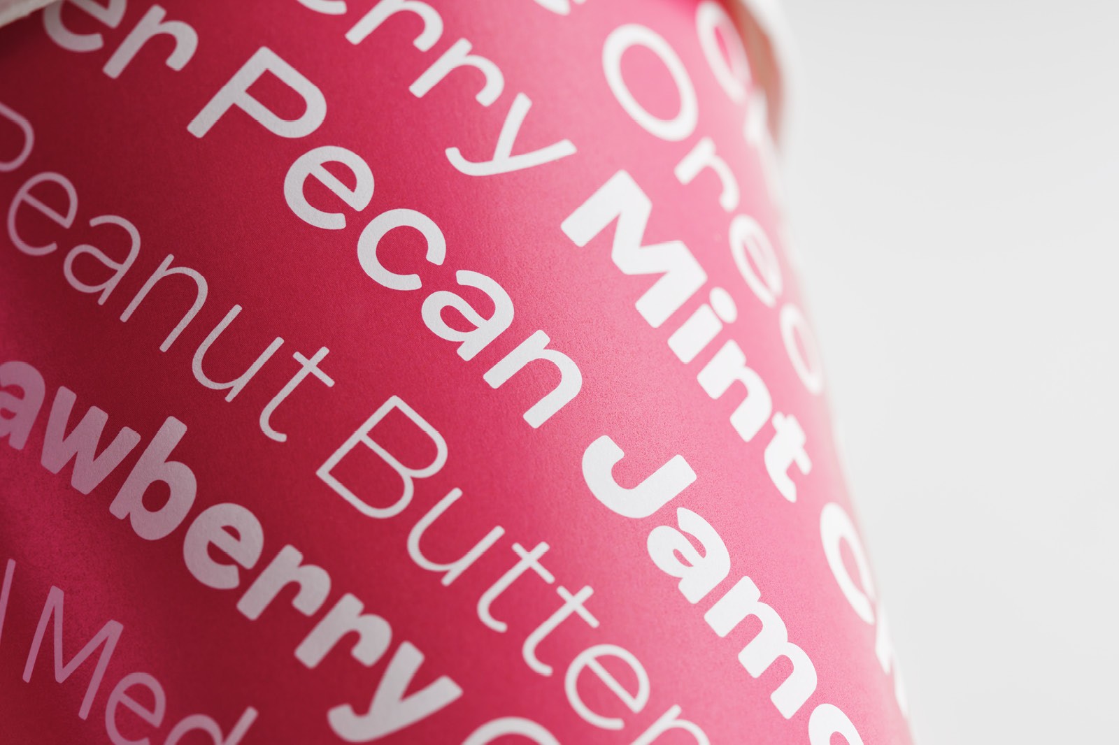Close-up of a pink surface featuring various jam flavors written in white text.