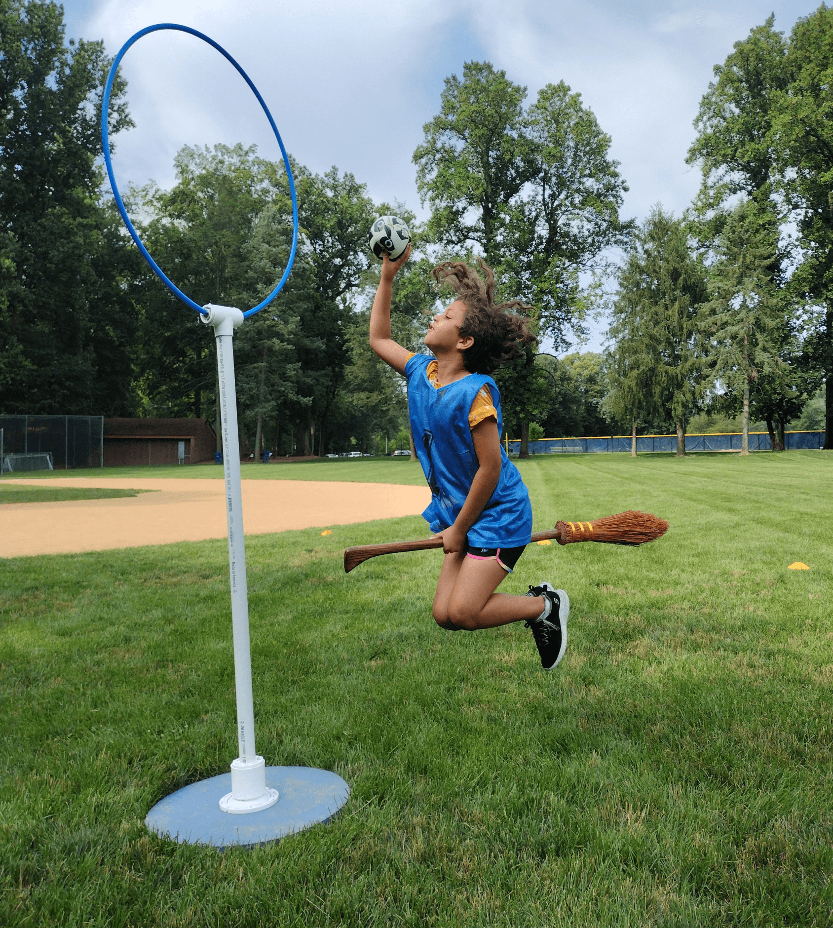A child with a broom launches a ball into the hoop 