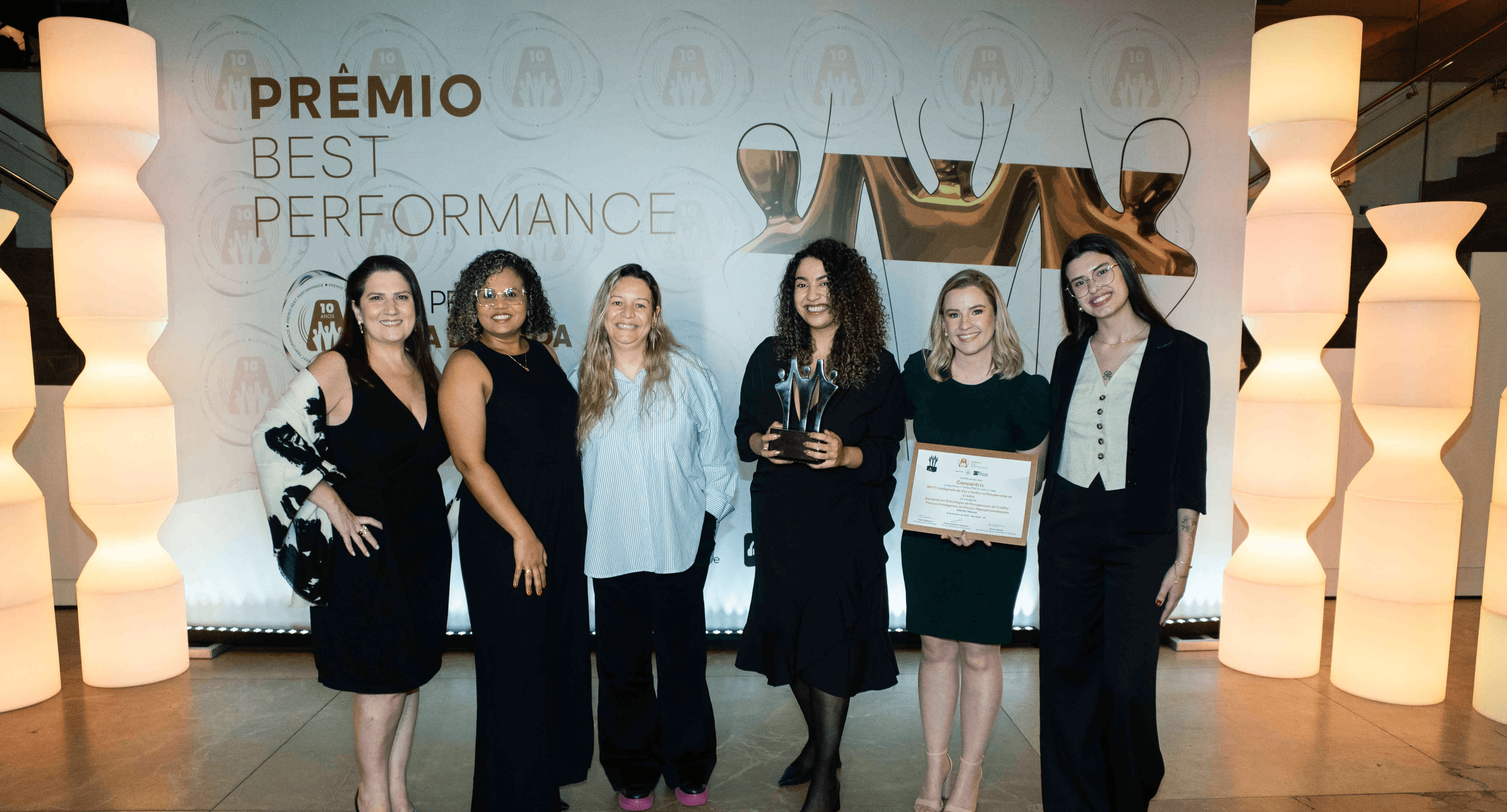 Executivos da Concentrix posando com troféu prata e certificado no palco do Prêmio Best Performance 2025