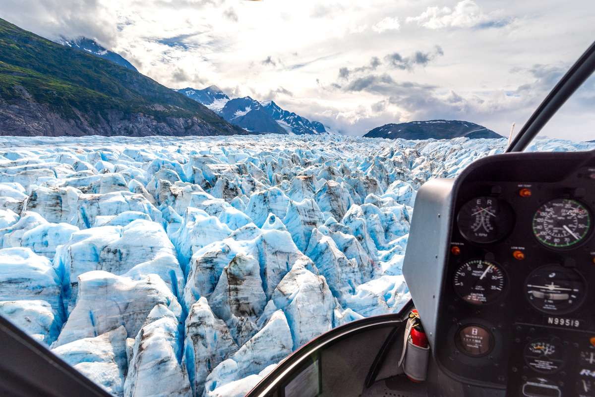View from a boat cockpit looking out over a vast field of blue and white ice chunks in a glacial lagoon.