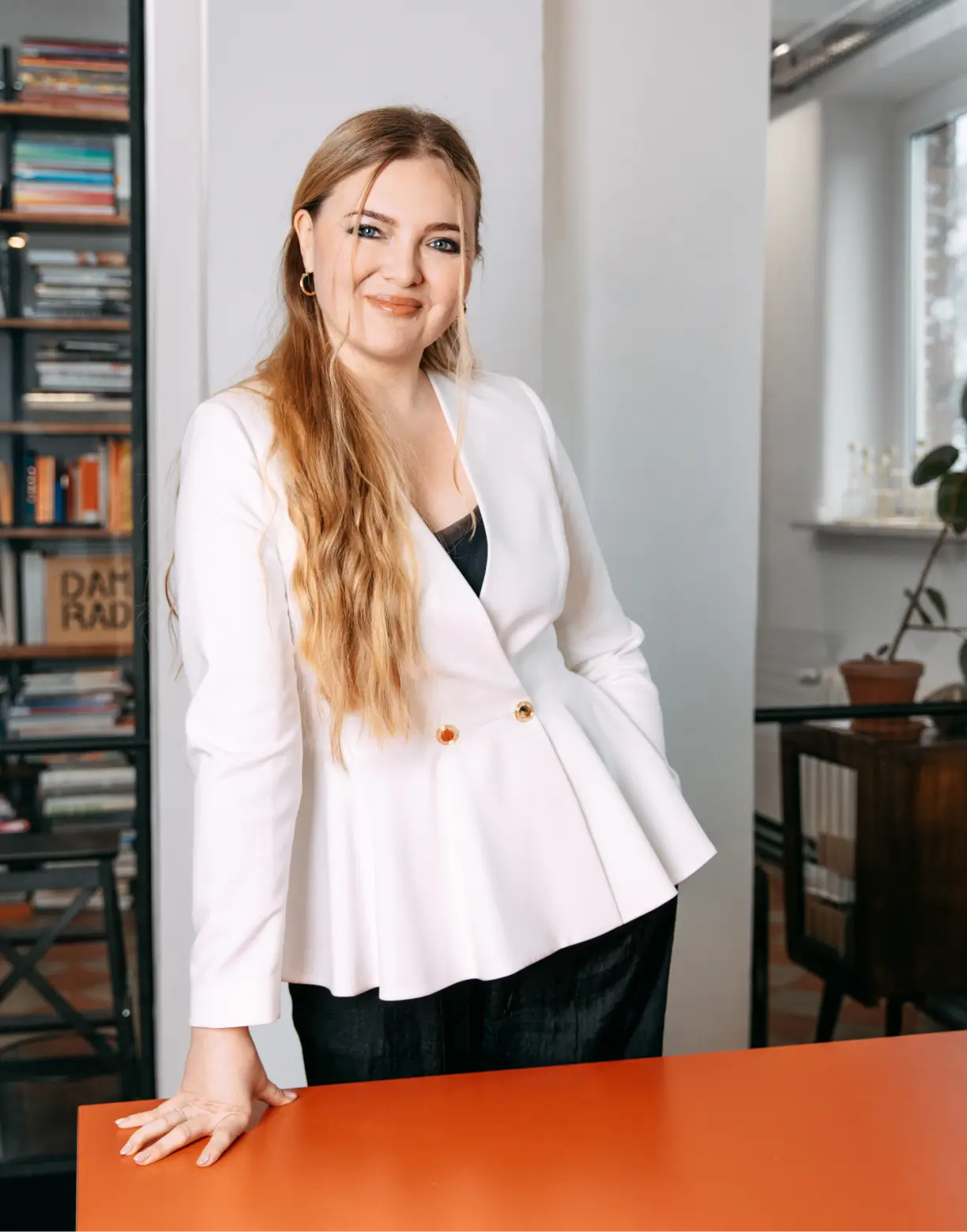 Portret kobiety w białej marynarce przy pomarańczowym stole