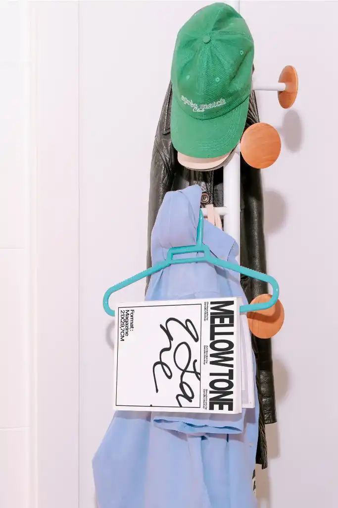 A stylish magazine with a hard cover and bold typography hangs on a teal hanger. The magazine blends modern design with casual aesthetics.