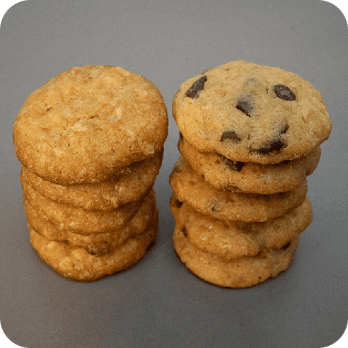 Torre de galletas mixtas: chocolate oscuro y blanco, hechas con masa madre, sobre fondo gris.
