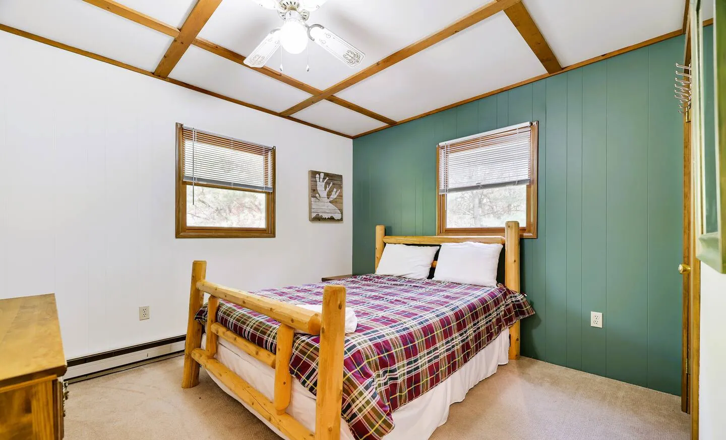 Upstairs bedroom with full log bed, plaid quilt and green accent wall at RedHawk Chalet