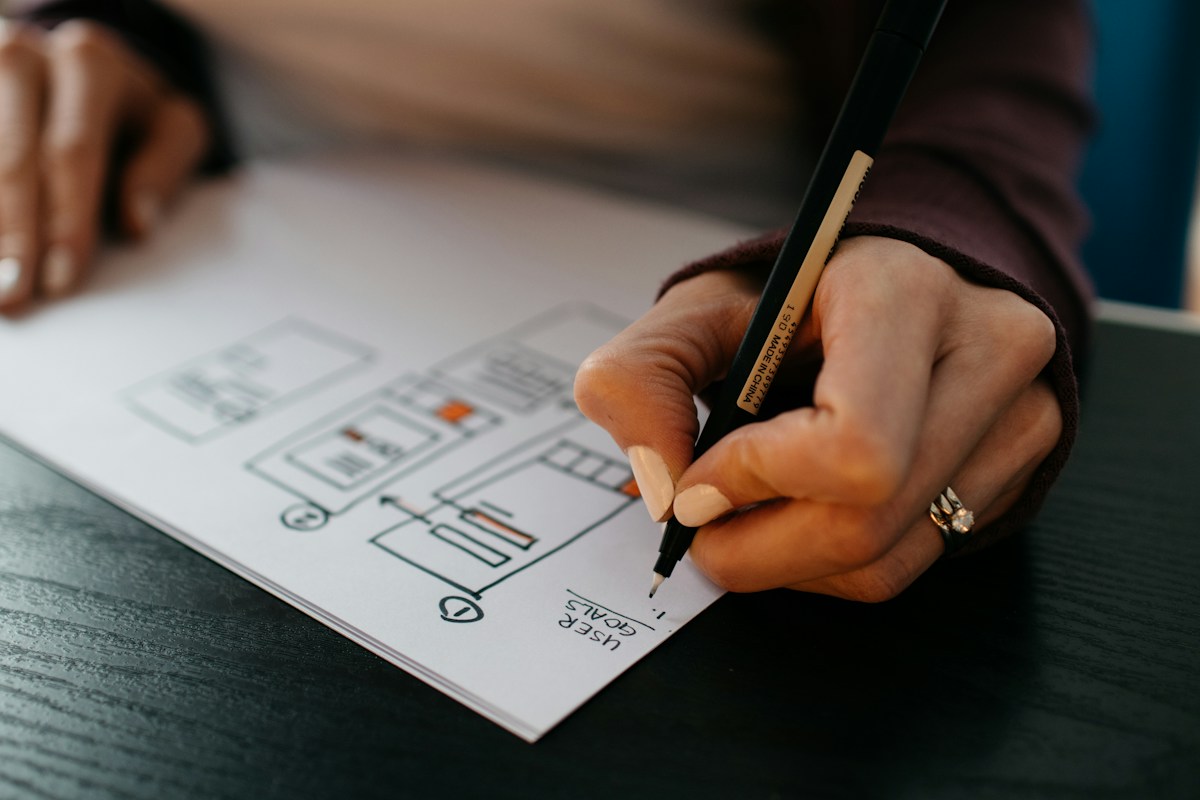 A hand sketching a floor plan in pencil