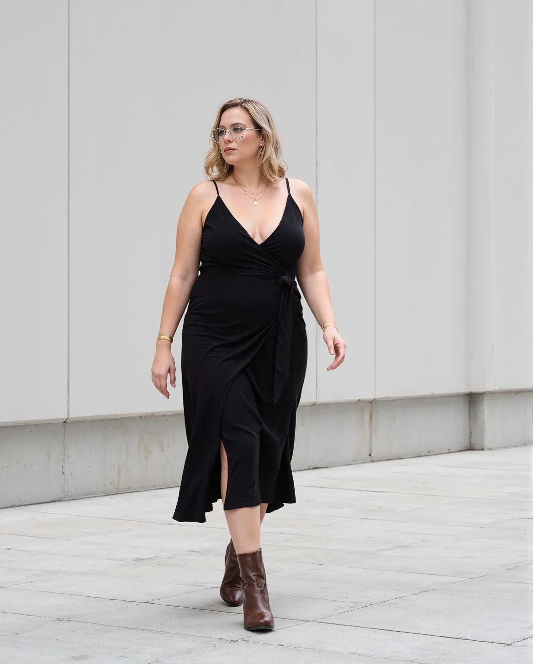 Elegant black wrap dress styled with brown leather ankle boots against minimalist white background, showcasing professional work attire