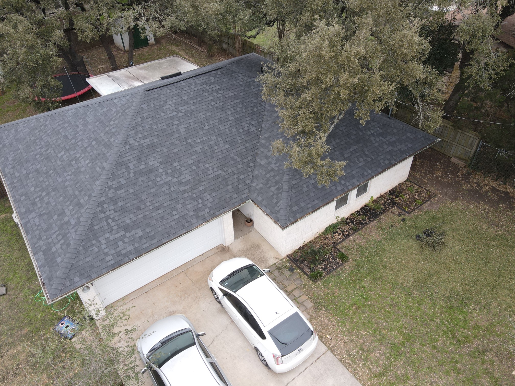 A one-story house with a charcoal-colored hip roof, featuring GAF HDZ Timberline architectural shingles. The roof has a smooth, sloping design with the dimensional shingles adding depth and texture. The charcoal color gives the home a modern, refined look, while the Timberline shingles provide long-lasting durability and protection.