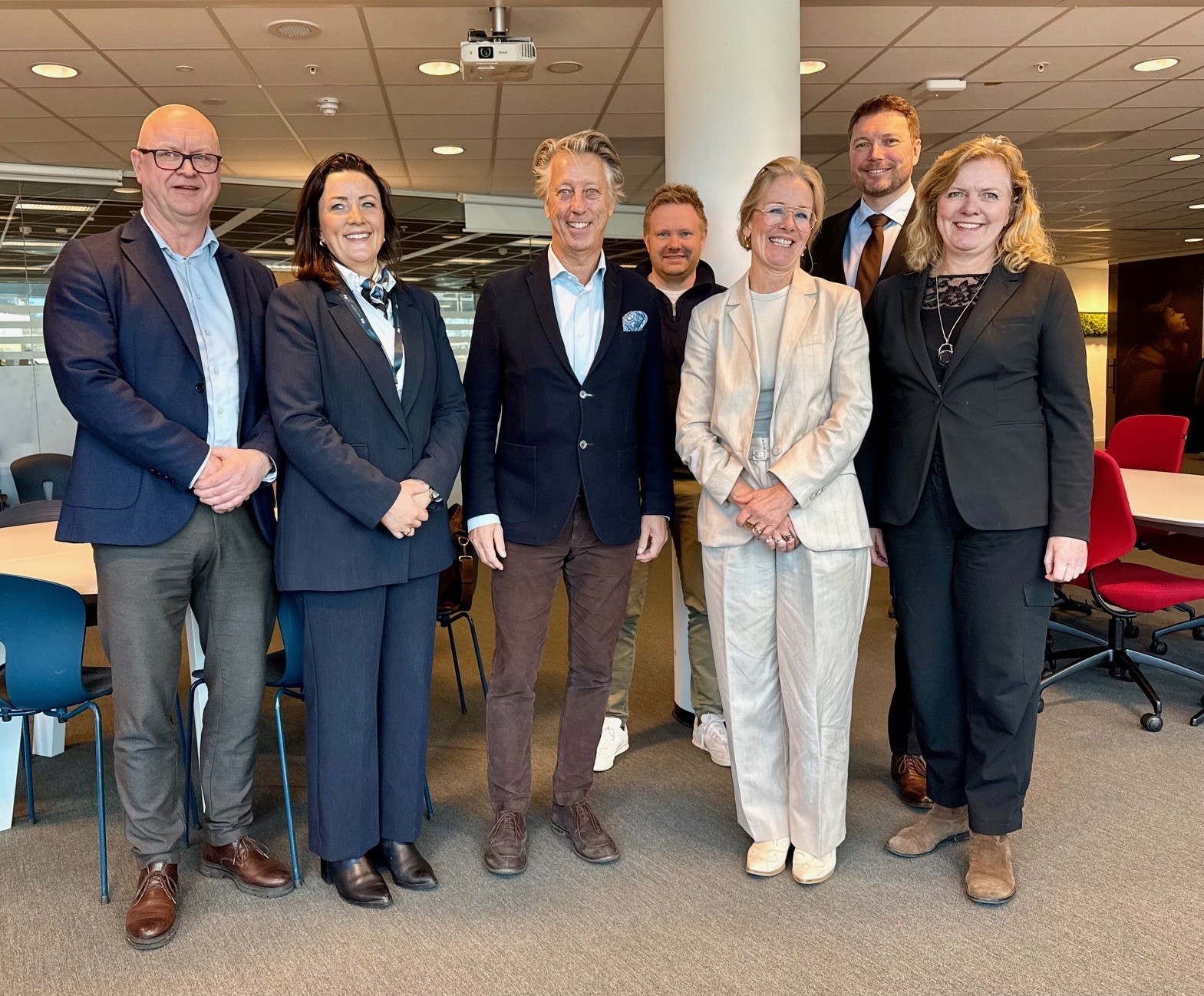 A person wearing a virtual reality headset stands in front of multiple screens, engaged in a digital experience.