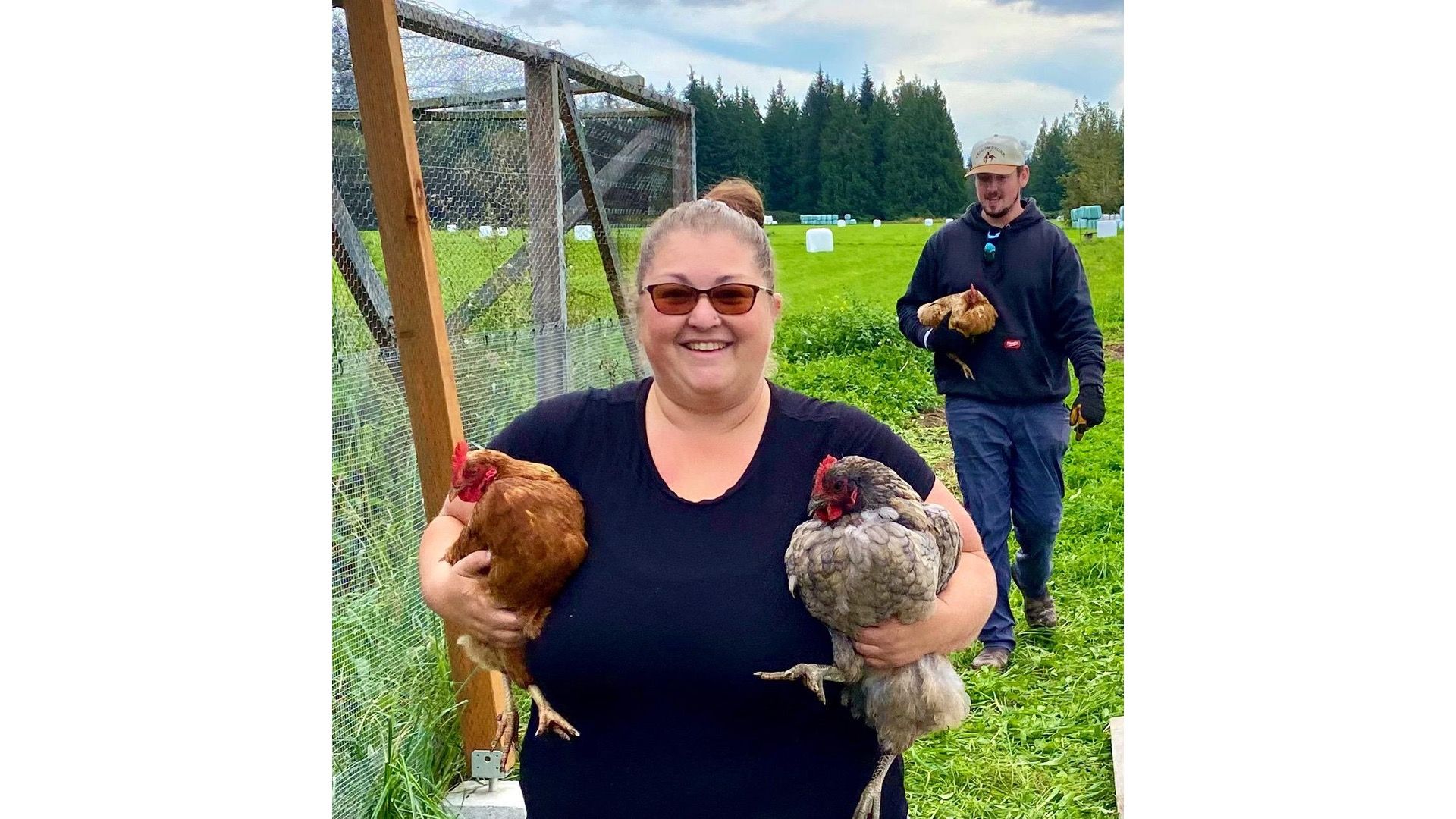 Jenn from Midgarden Farm carrying two chickens across the fields at Rooted Northwest