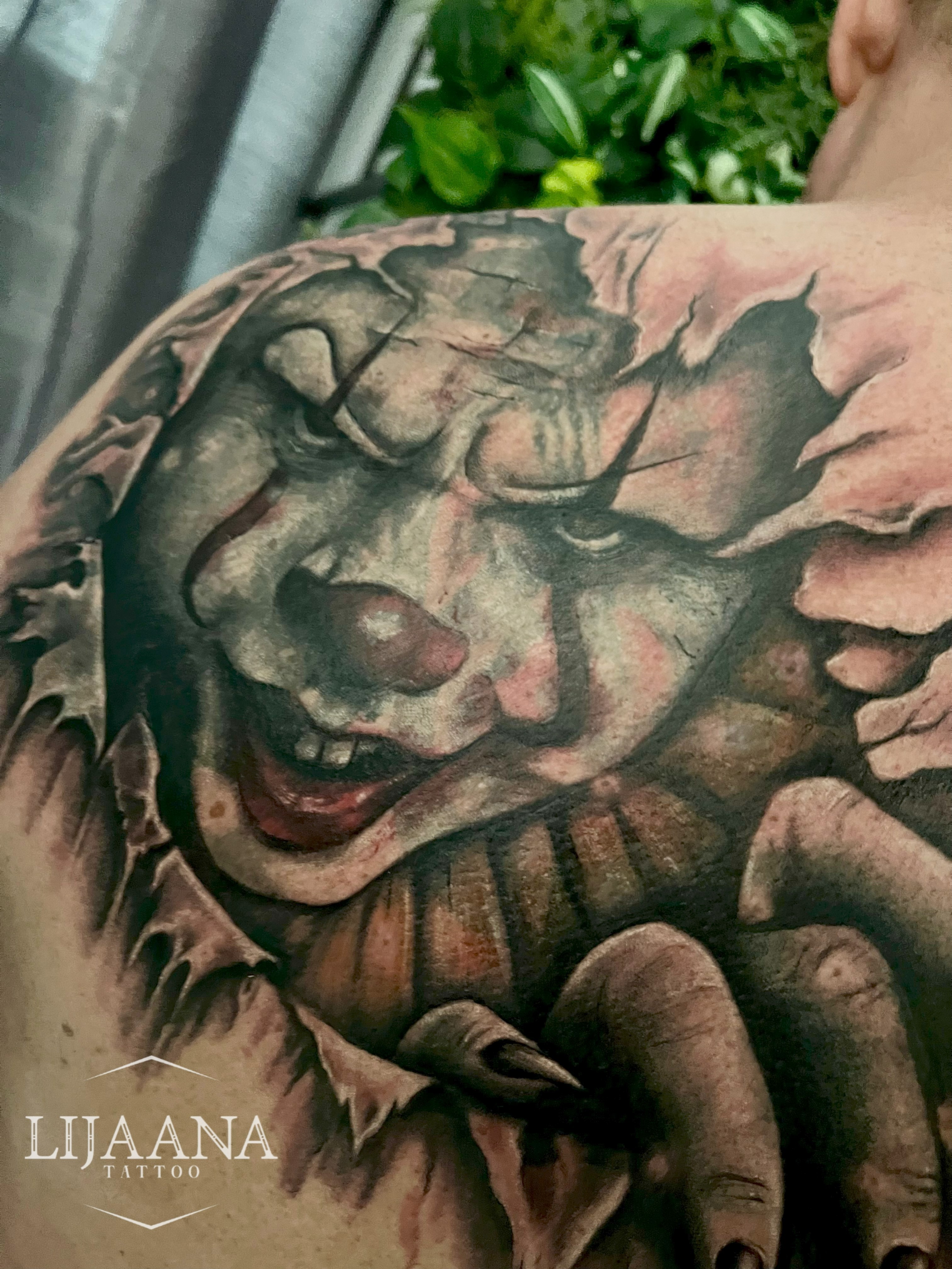 Realistic Pennywise horror tattoo on shoulder with black and grey shading by Lijaana Tattoo in Helsinki.