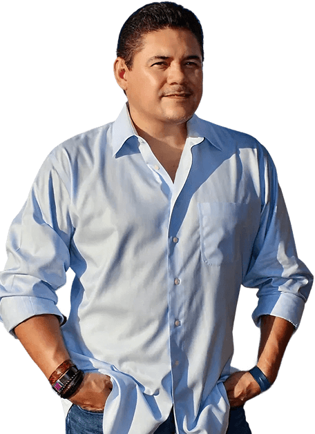 Asian man with glasses in a creative workspace, surrounded by colorful abstract art and stationery on a cluttered desk.