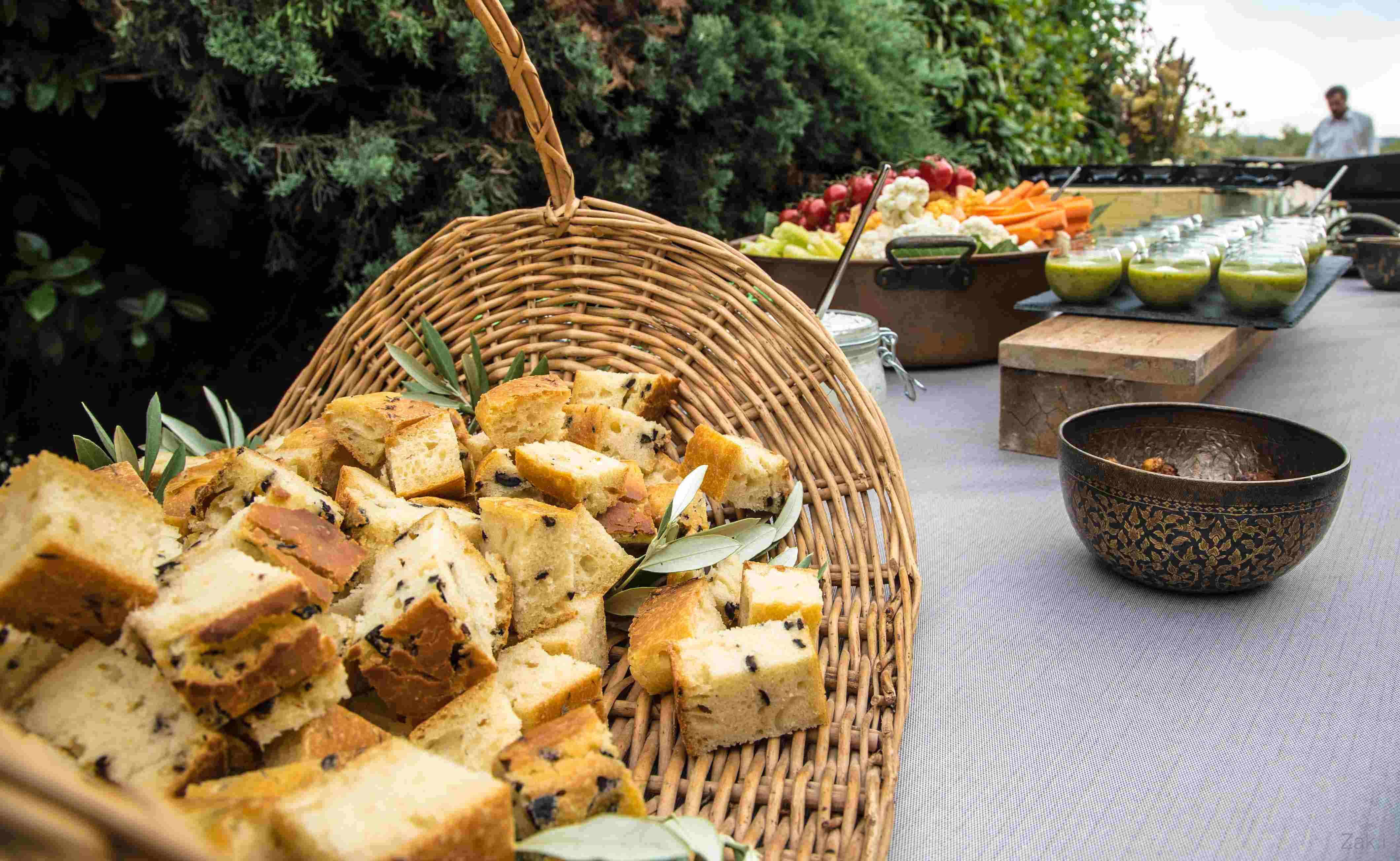 Buffet traiteur en extérieur avec pains maison, légumes frais et verrines pour cocktail ou réception en plein air.