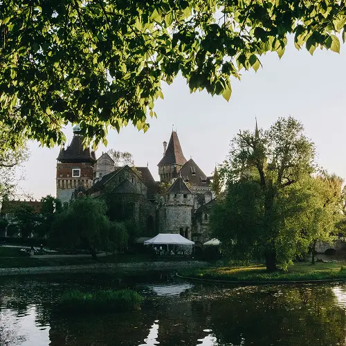 Panoramic view of historic Sudeley Castle across the lake with lush gardens and trees in the Cotswolds