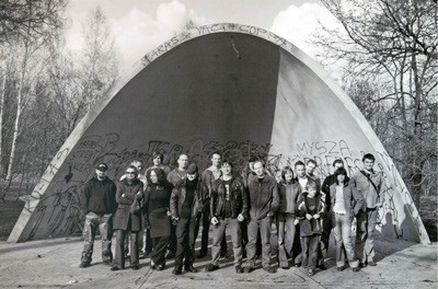 plakat 20 inicjatywy zdjęcia grupowego, napis namalowany pędzlem, informacje na karteczce memo oraz poprzednie zdjęcia przedstawione w formie wieży