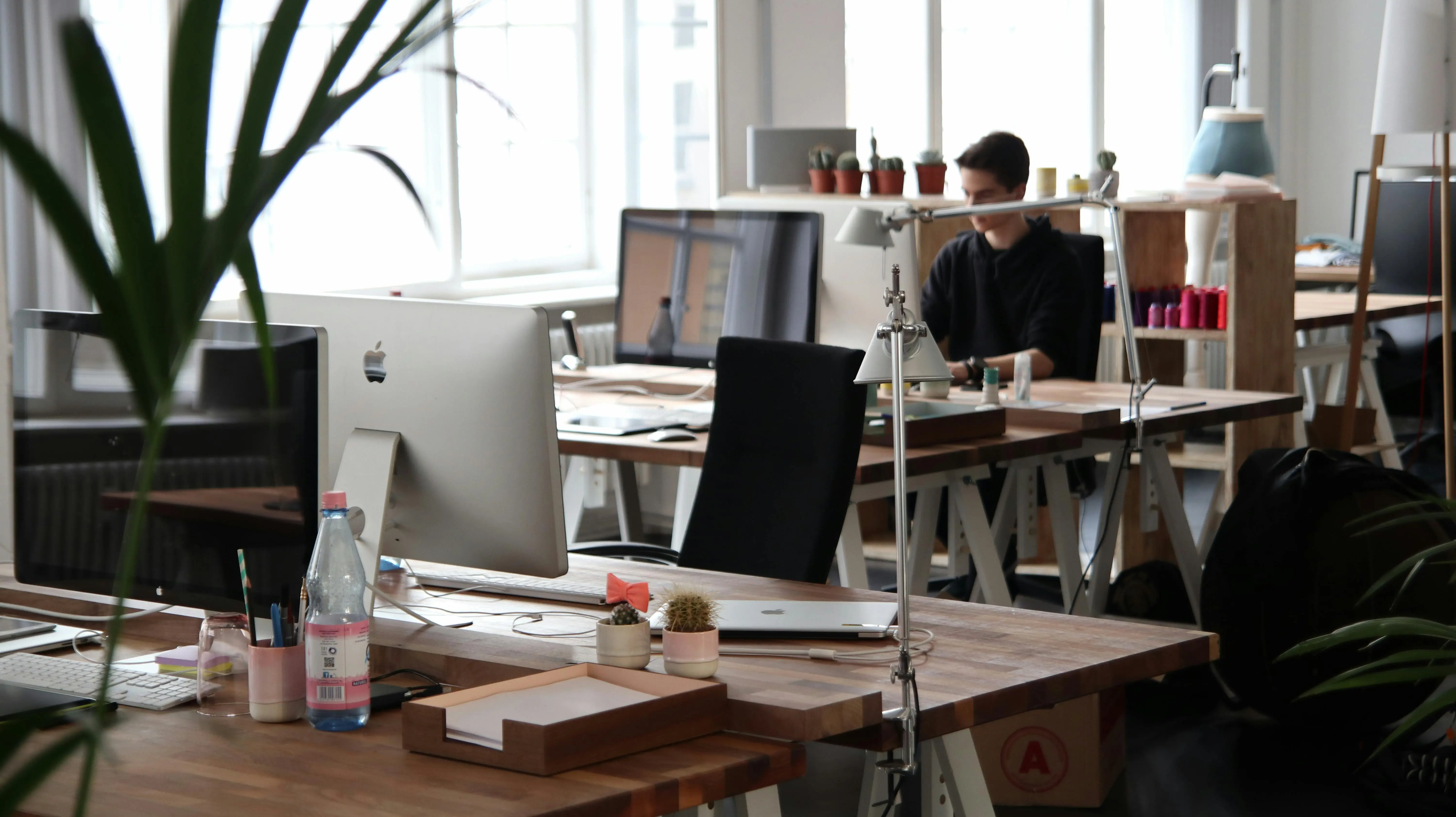 A bright, modern office space with wooden desks and computers.