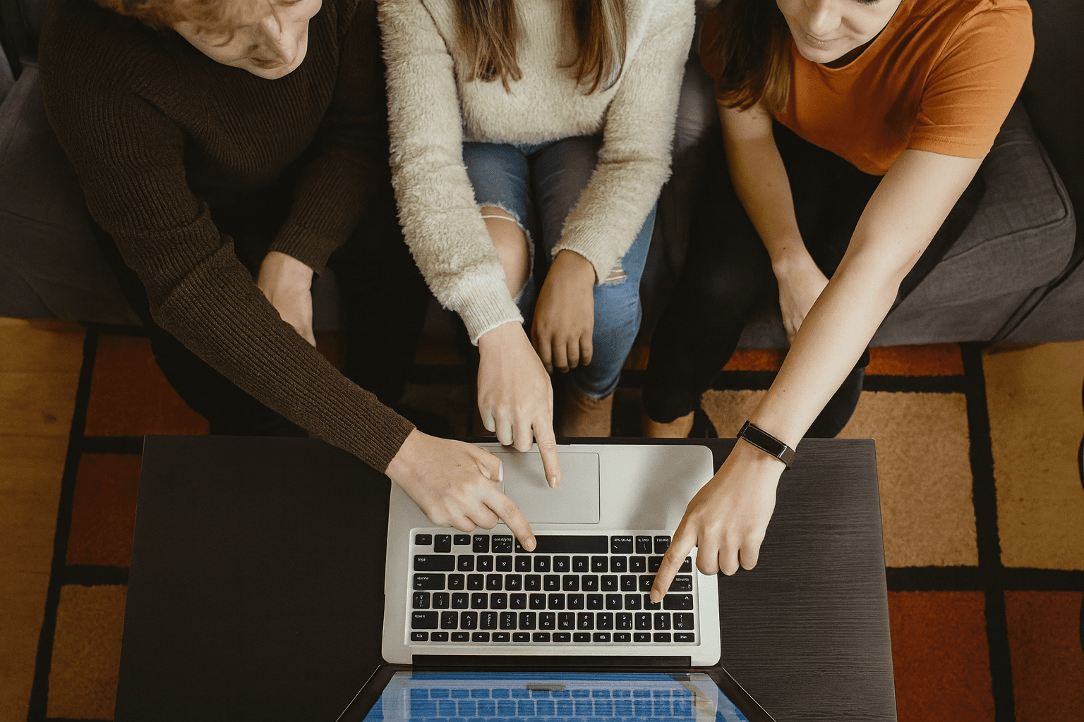 Trois personnes assises autour d'un ordinateur portable, pointant l'écran, symbolisant la collaboration et la prise de décision pour vendre efficacement sur Amazon, une plateforme reconnue mondialement.