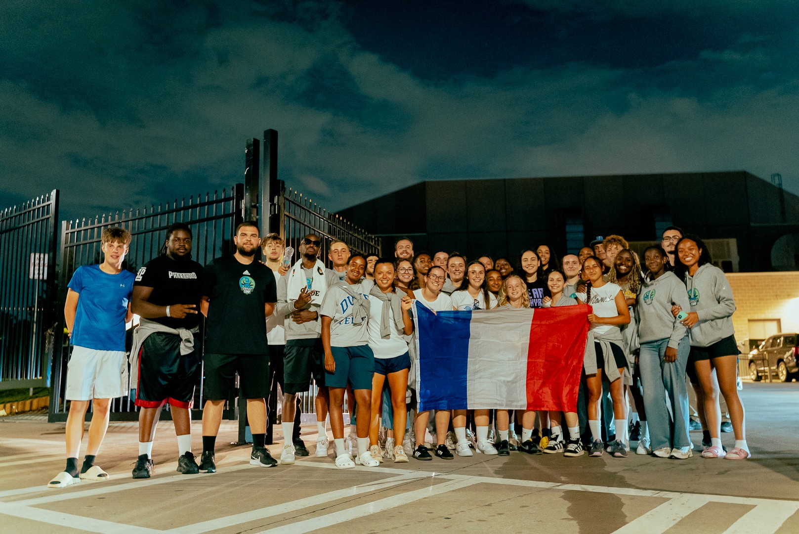 Groupe de participants du Combine Elite Camp après un match WNBA, tenant un drapeau français.