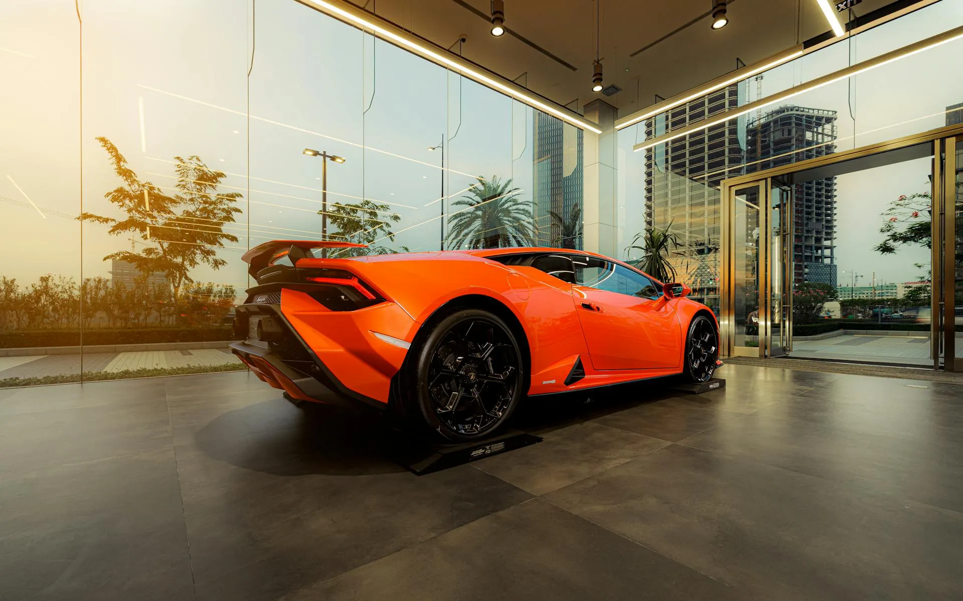Car dealership showroom interior with a sports car displayed inside a modern glass building