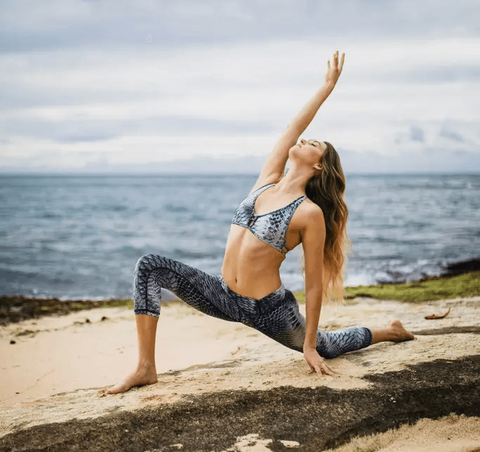 Yoga student performing a low lunge asana variation on the rocks at Bingin Beach Bali.