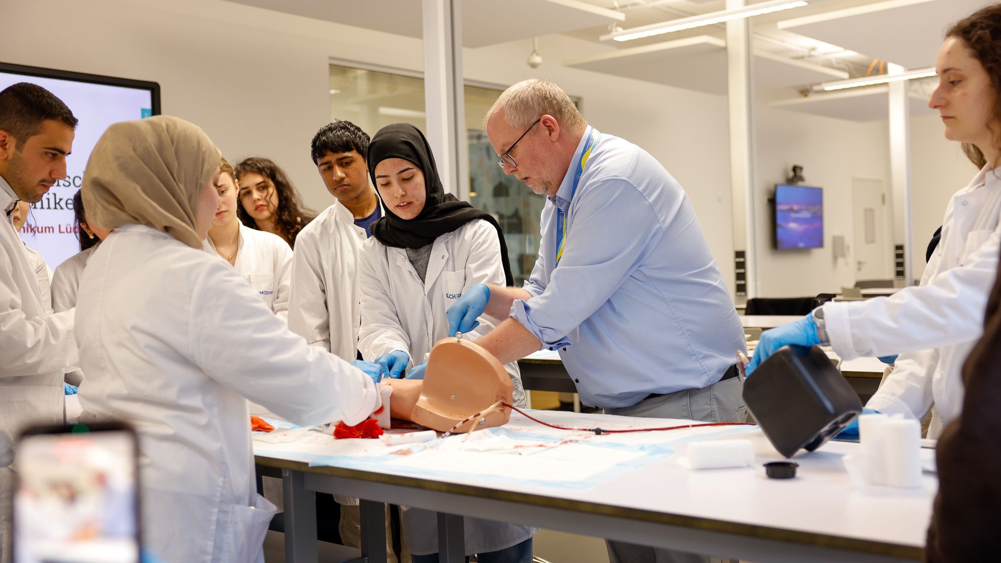 Students in white coats at a UMCH skills workshop