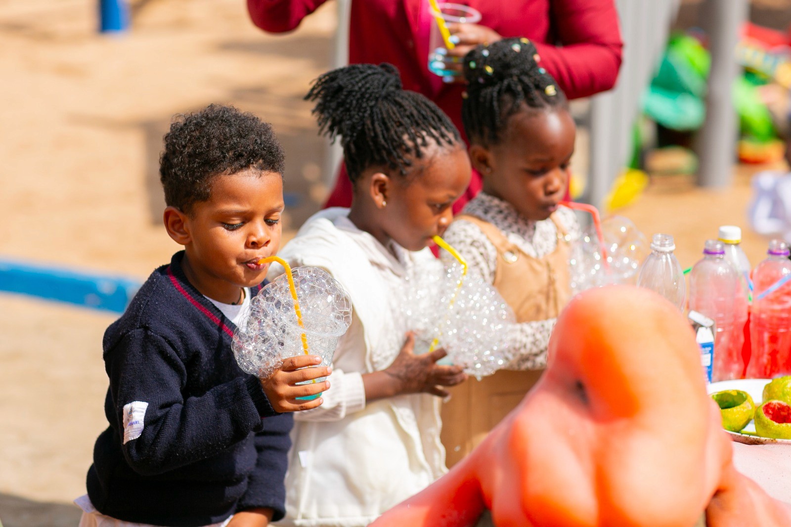 A student wearing a red uniform sits while holding a book in his hands