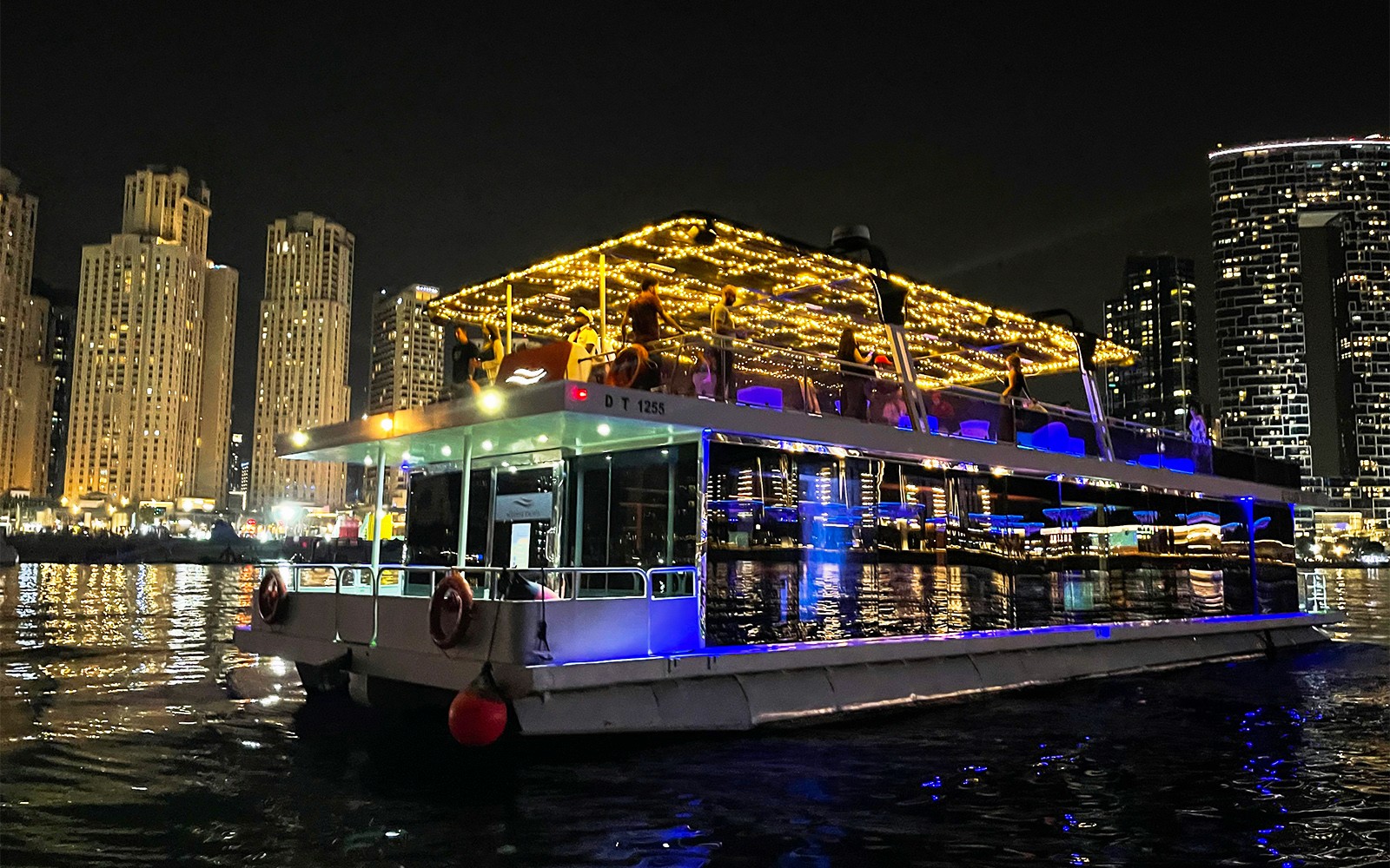 Hausboot mit Lichtern auf der Dubai Marina bei Nacht während der Ain Dubai Tour.