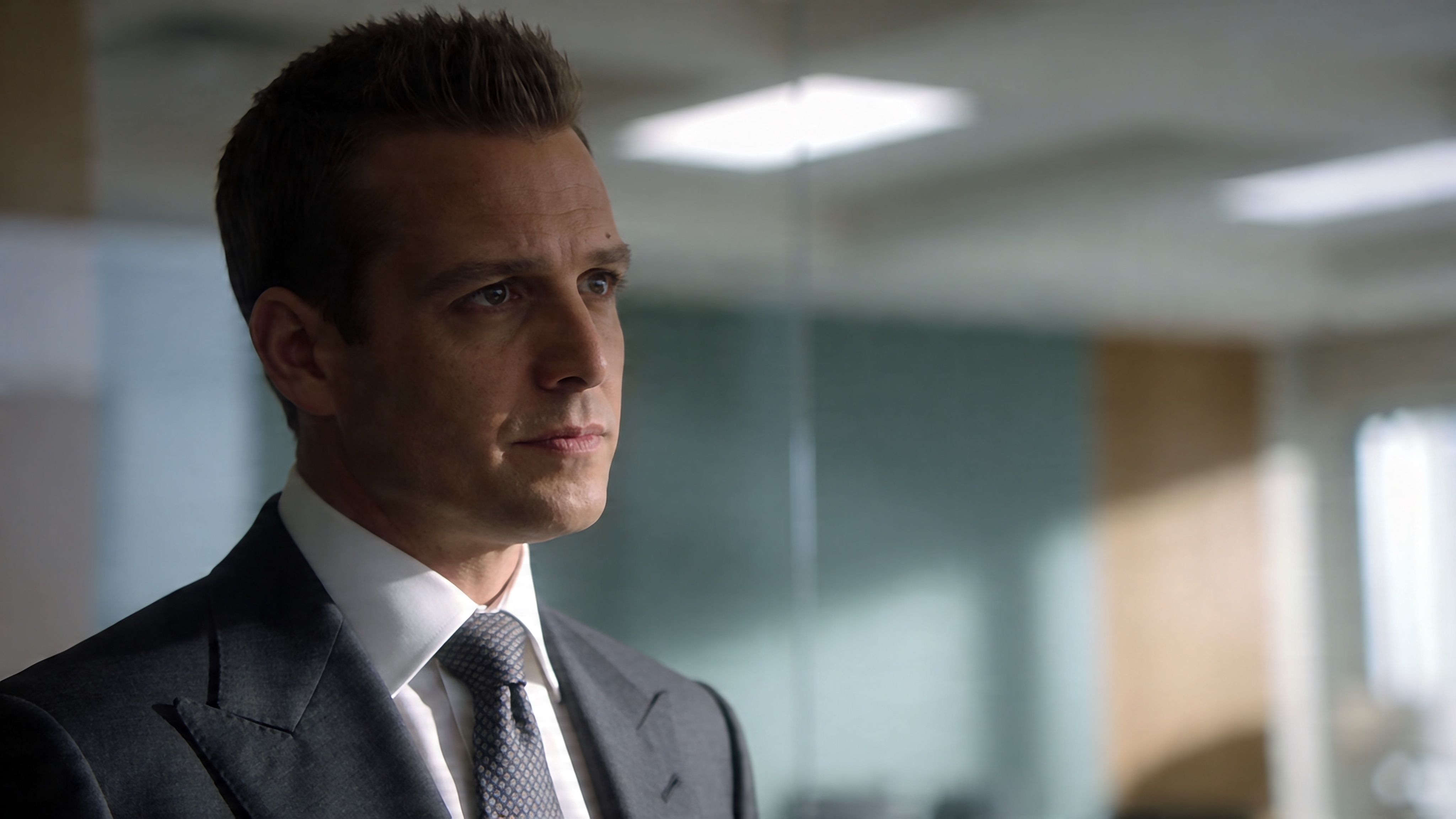 Ein fokussierter Geschäftsmann im Anzug mit Krawatte schaut nachdenklich in einem modernen Büro in die Ferne.