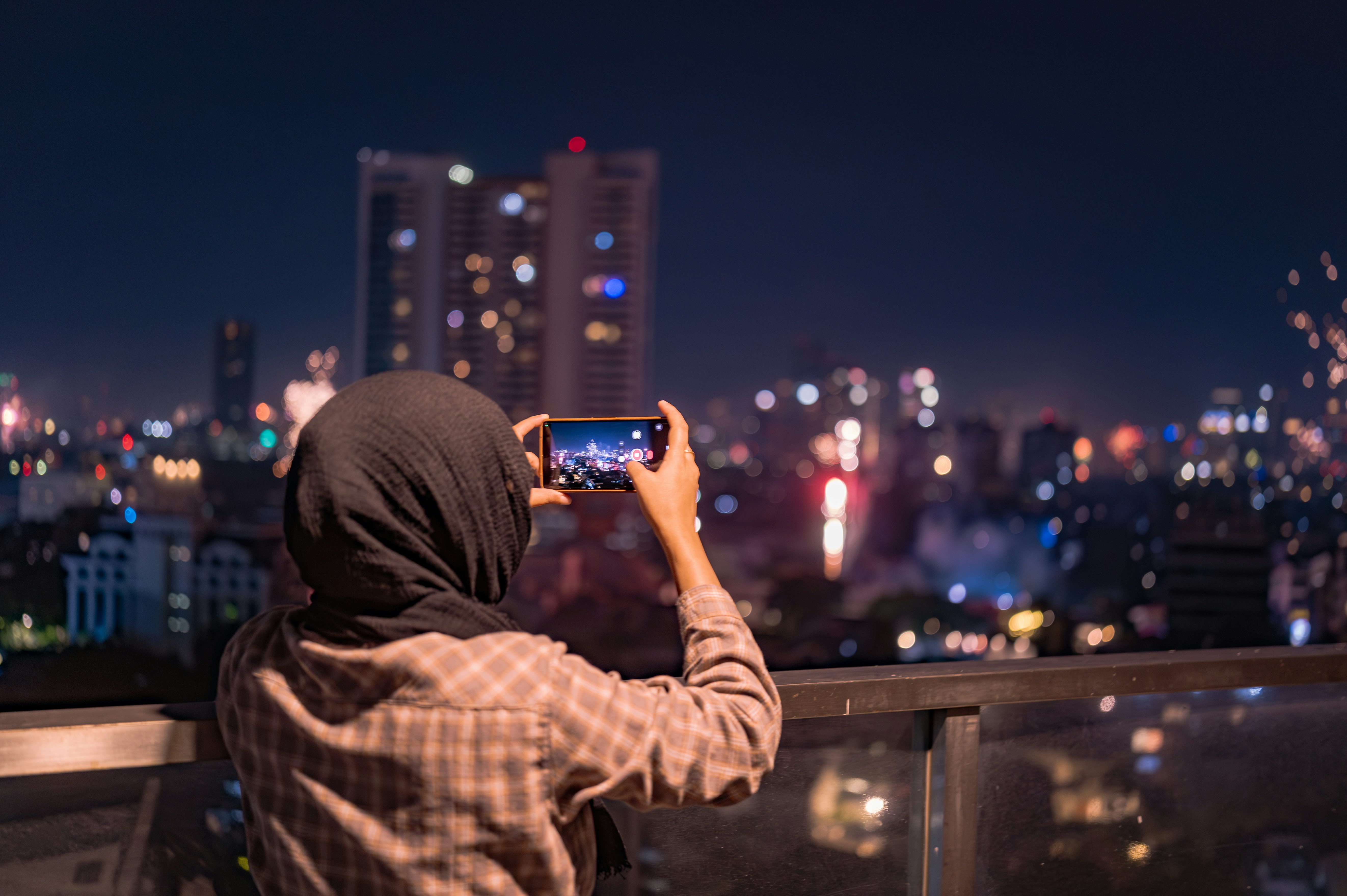 A person taking a picture of a city at night