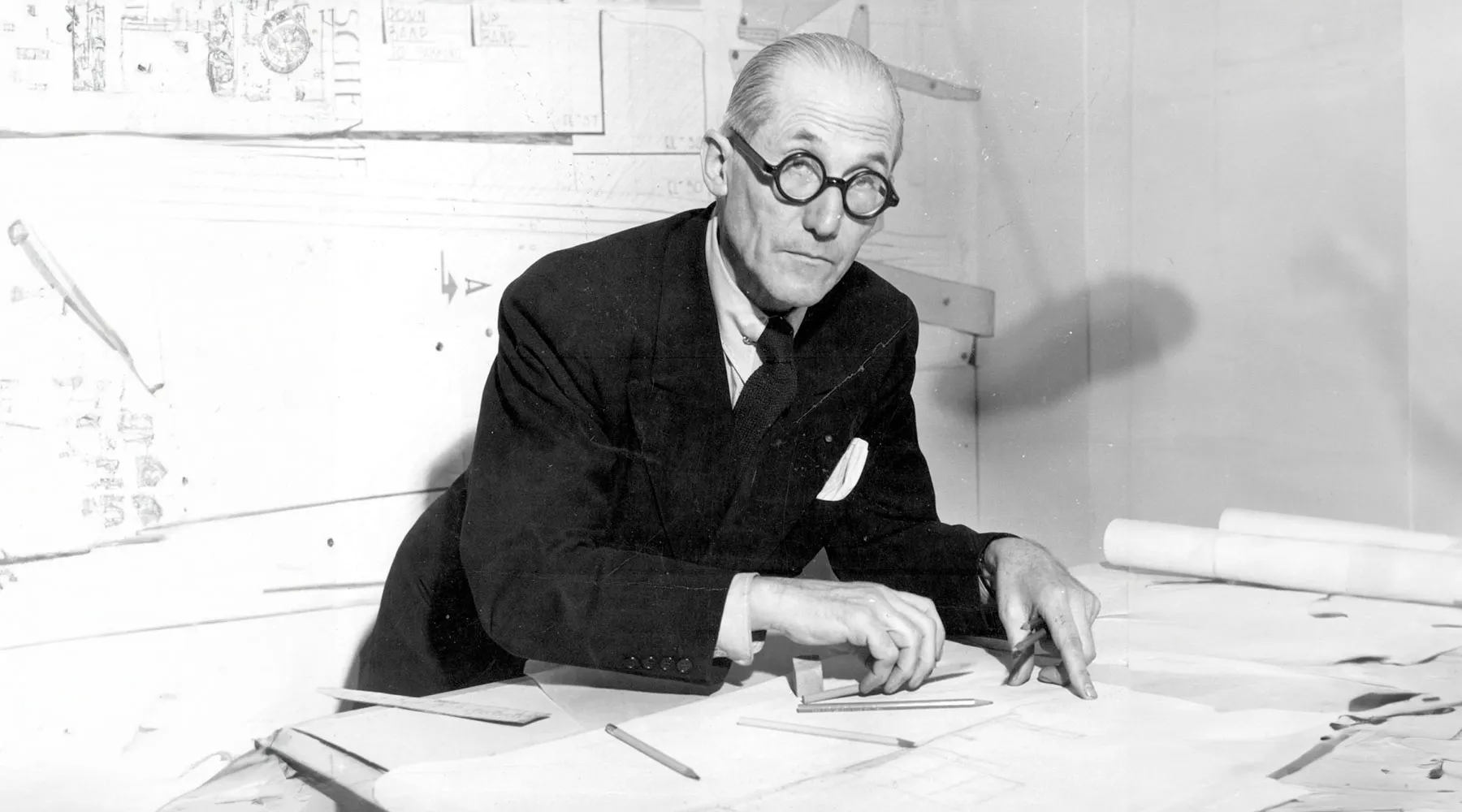 Le Corbusier sitting at a drafring table