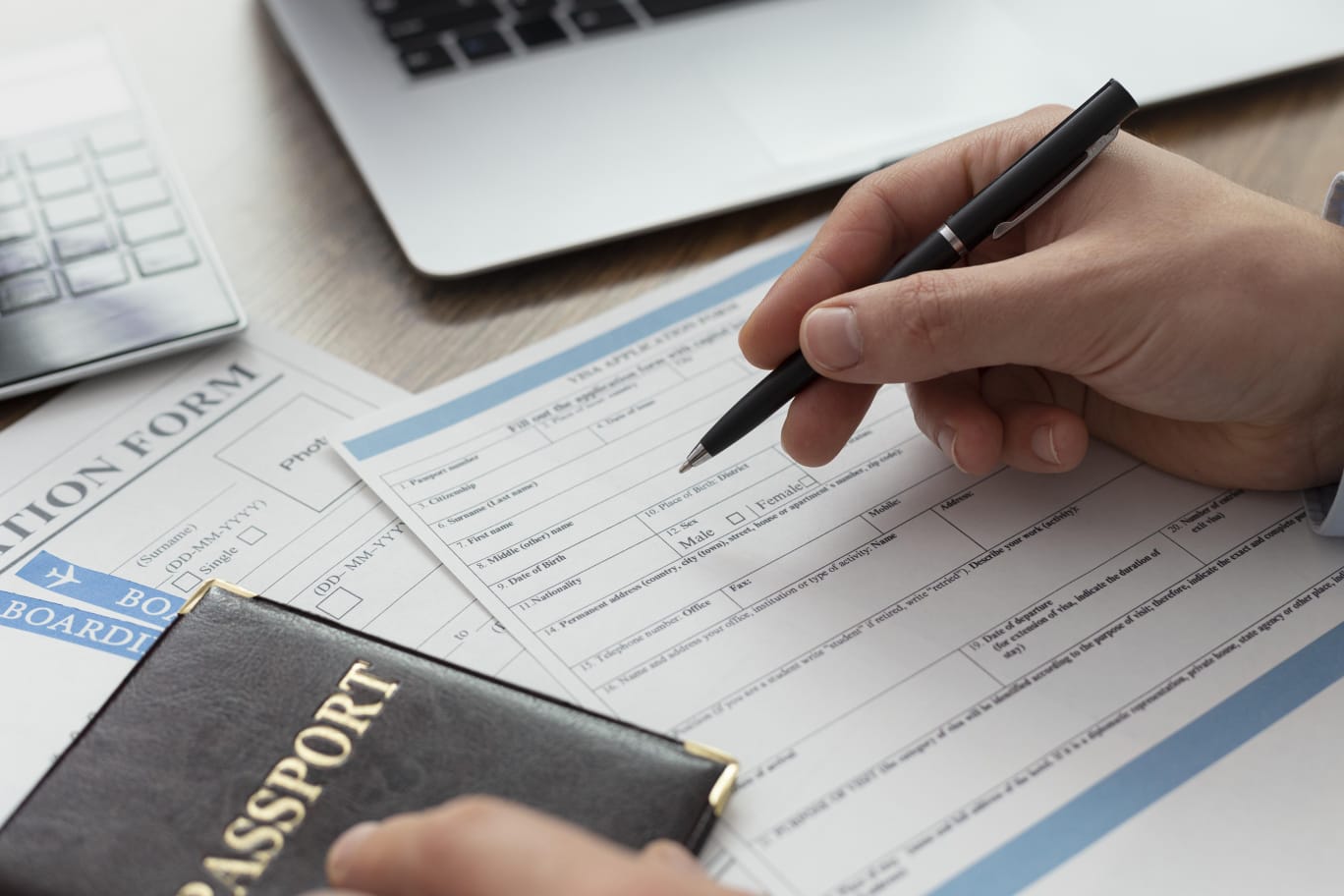 Photo of a man's hand filling a UAE residency visa form for RAKEZ company formation.