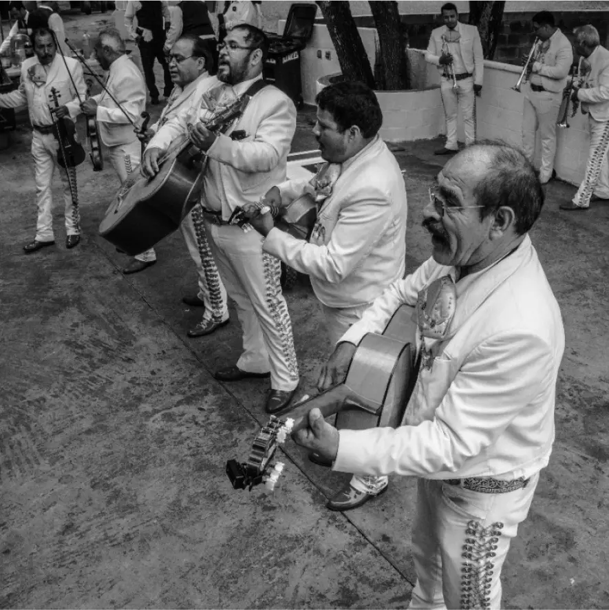 A mariachi band is performing with guitars, violins, and trumpets at a local restaurant.