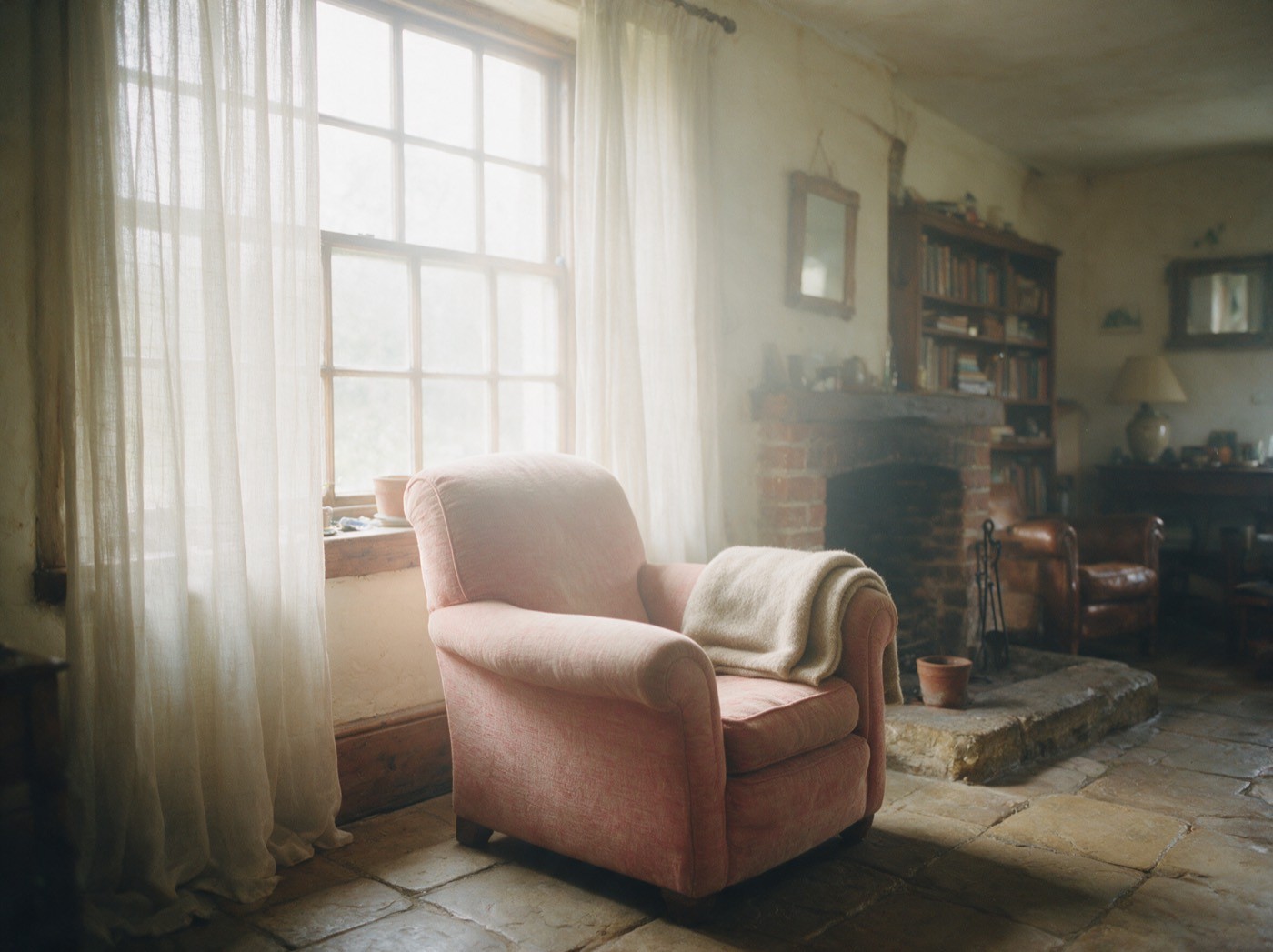An empty armchair beside a window in a quiet sitting room