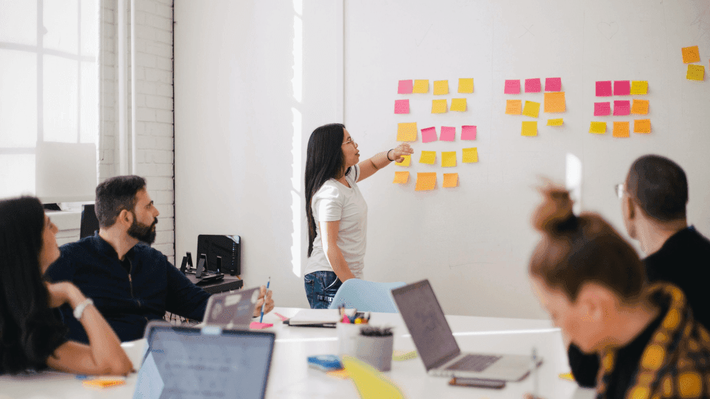 team member at board pointing at sticky notes