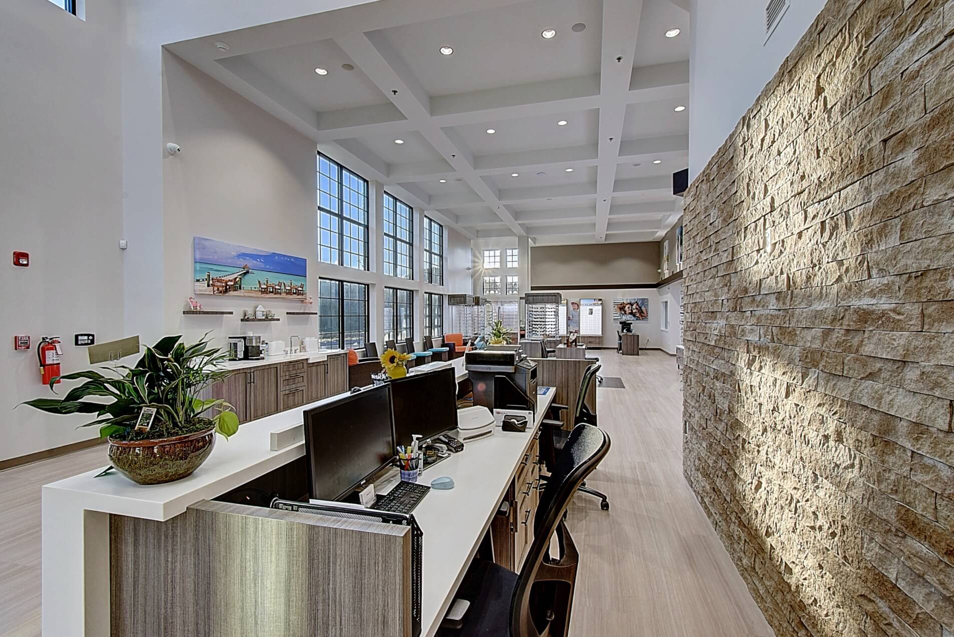 Modern interior with high ceilings, large windows, and a stylish stone wall, showcasing a sleek retail space.