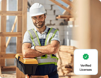 Contractor wearing a hard hat and safety vest smiling on site with a “Verified License” badge overlay, symbolising qualification verification.