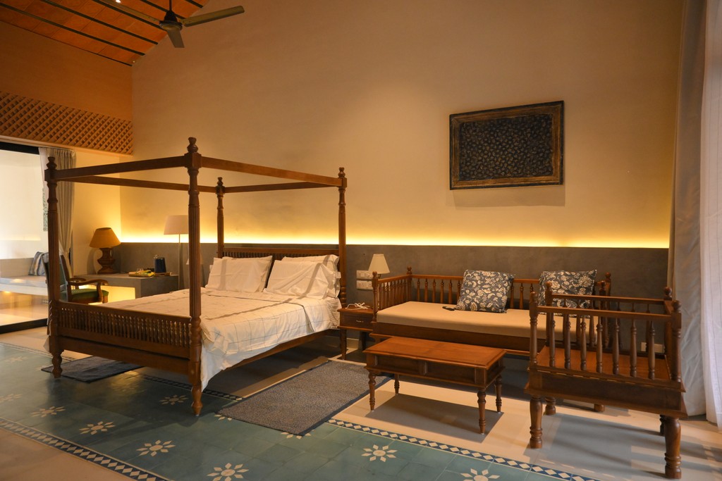 A luxurious bathtub filled with water and floating rose petals, surrounded by candles and greenery. The soft lighting creates a tranquil and romantic spa-like atmosphere.