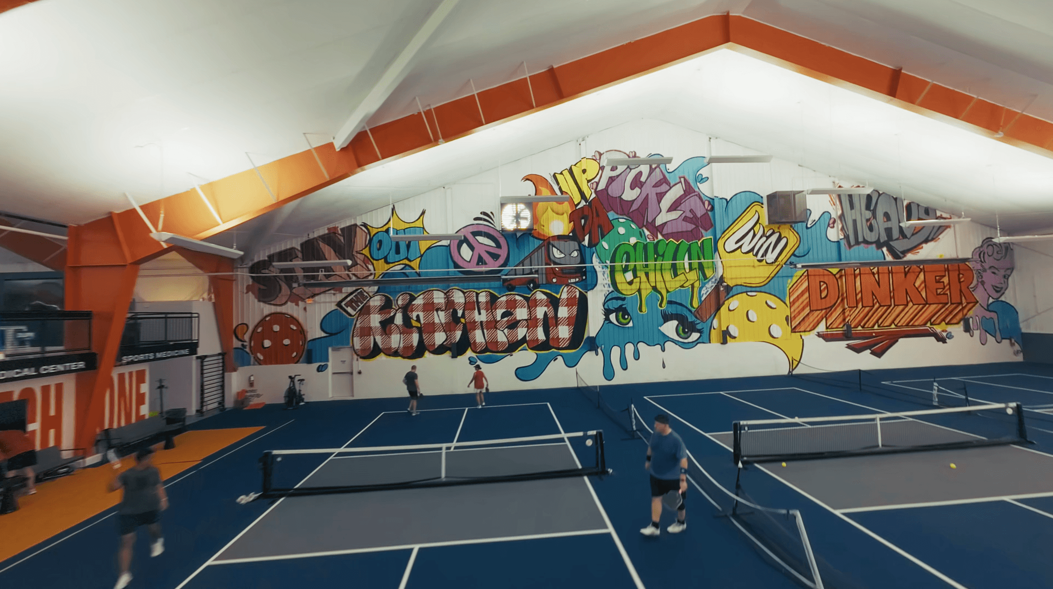 Spacious, luxurious living room with high ceilings, an elegant beige sectional sofa, warm ambient lighting, classical artwork, and rustic architectural elements, featuring an open layout with a view of a mezzanine level.