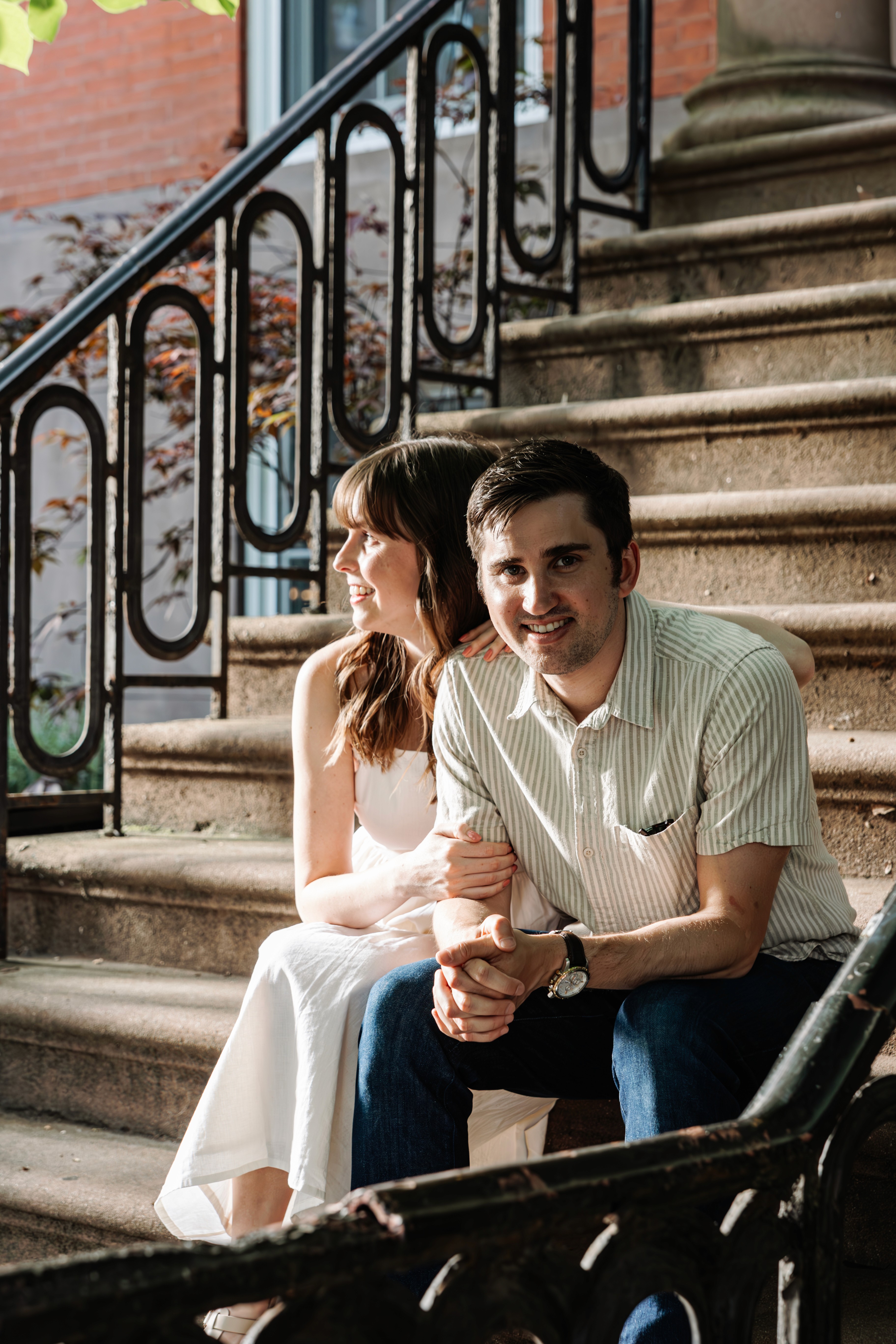 6:13 PMNewly engaged couple sitting on a stoop in the West Village, NYC bathed in warm golden hour light — romantic, candid golden hour engagement photography by Lizz Spano Photography, New York City engagement photographer.