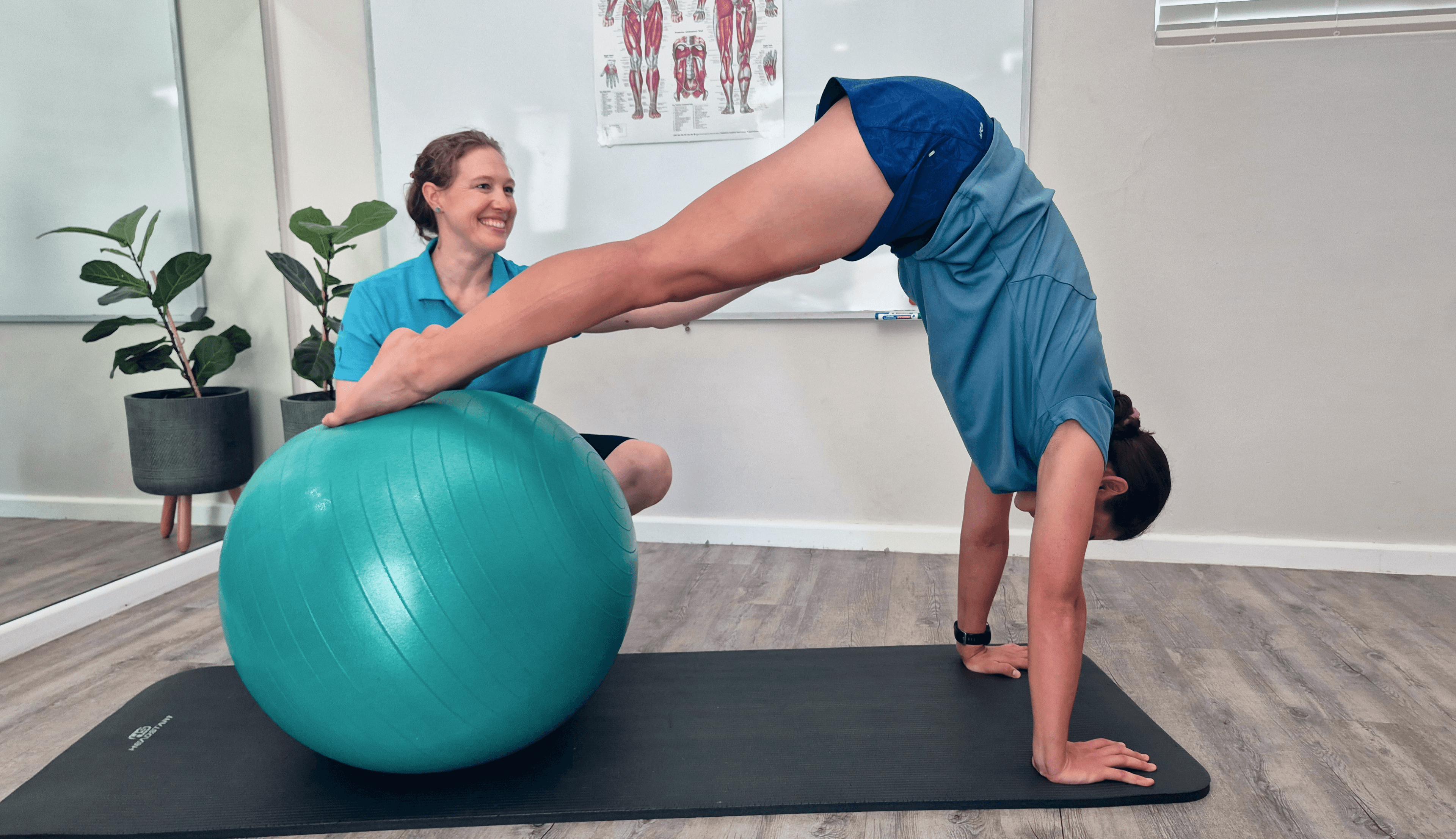 A patient performs a strength and conditioning exercise on a stability ball while the Physiotherapist assists them