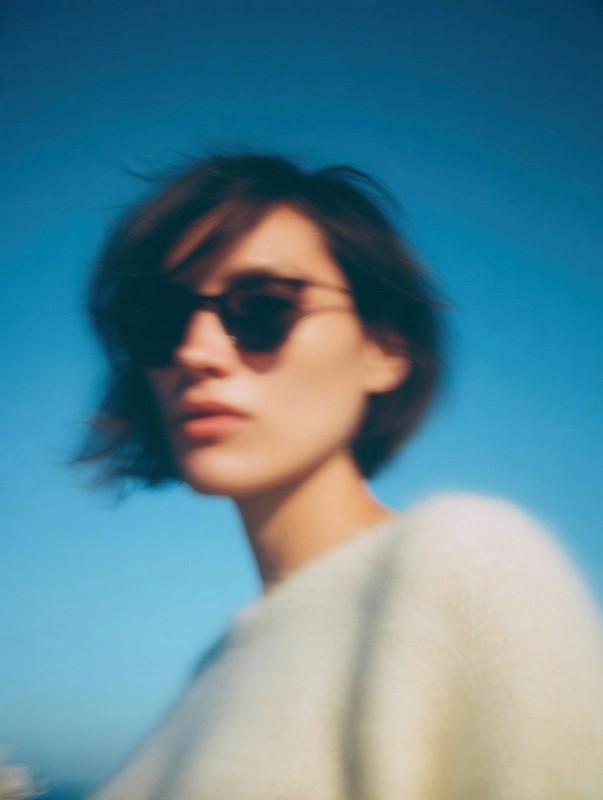 Portrait of a woman with short hair and sunglasses against a clear blue sky