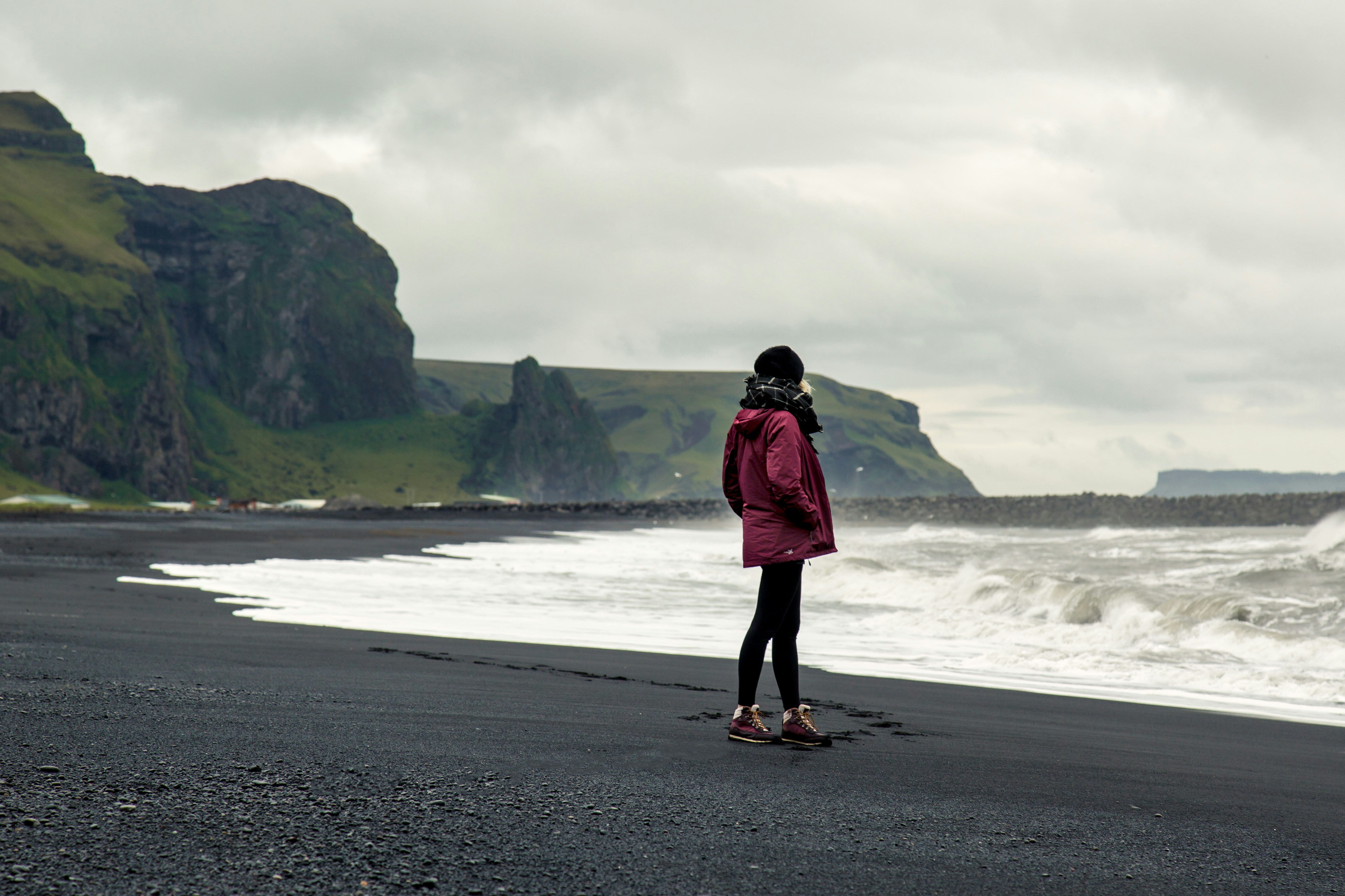 A woman standing on a beach next to the ocean