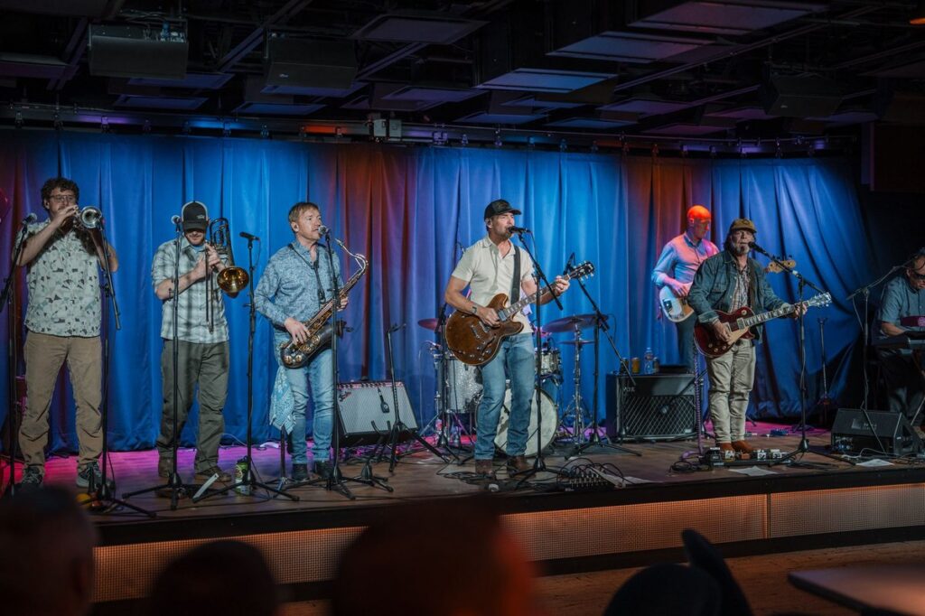Live band performing on the Paul JAS Center stage during Aspen corporate event with blue stage lighting and full horn section