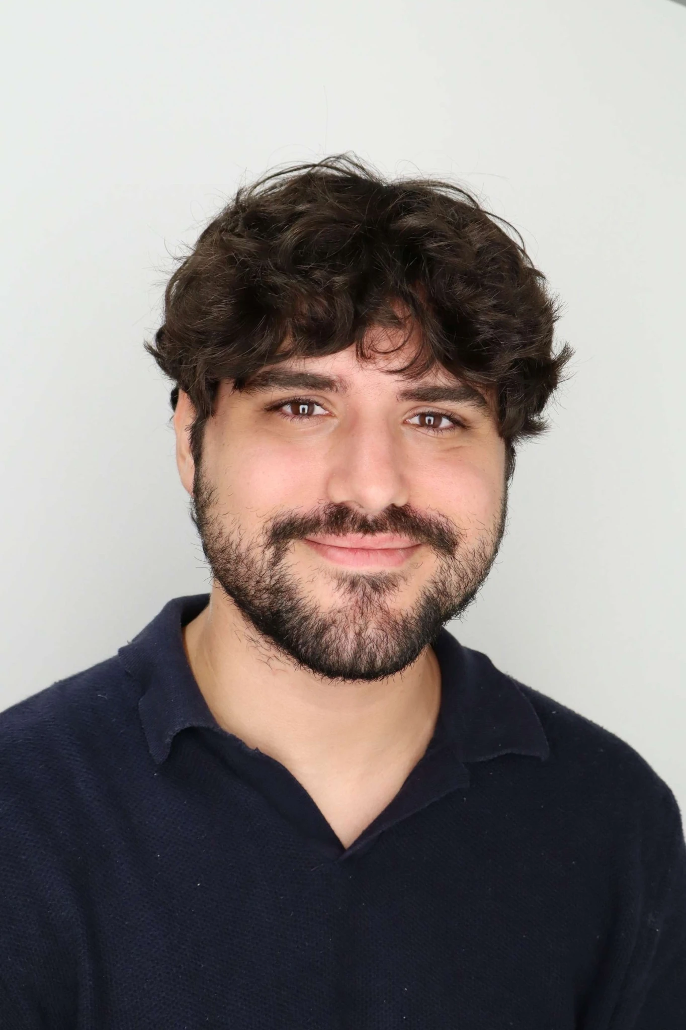 A thoughtful young person with dark hair gazes to the side, captured in soft black and white lighting.